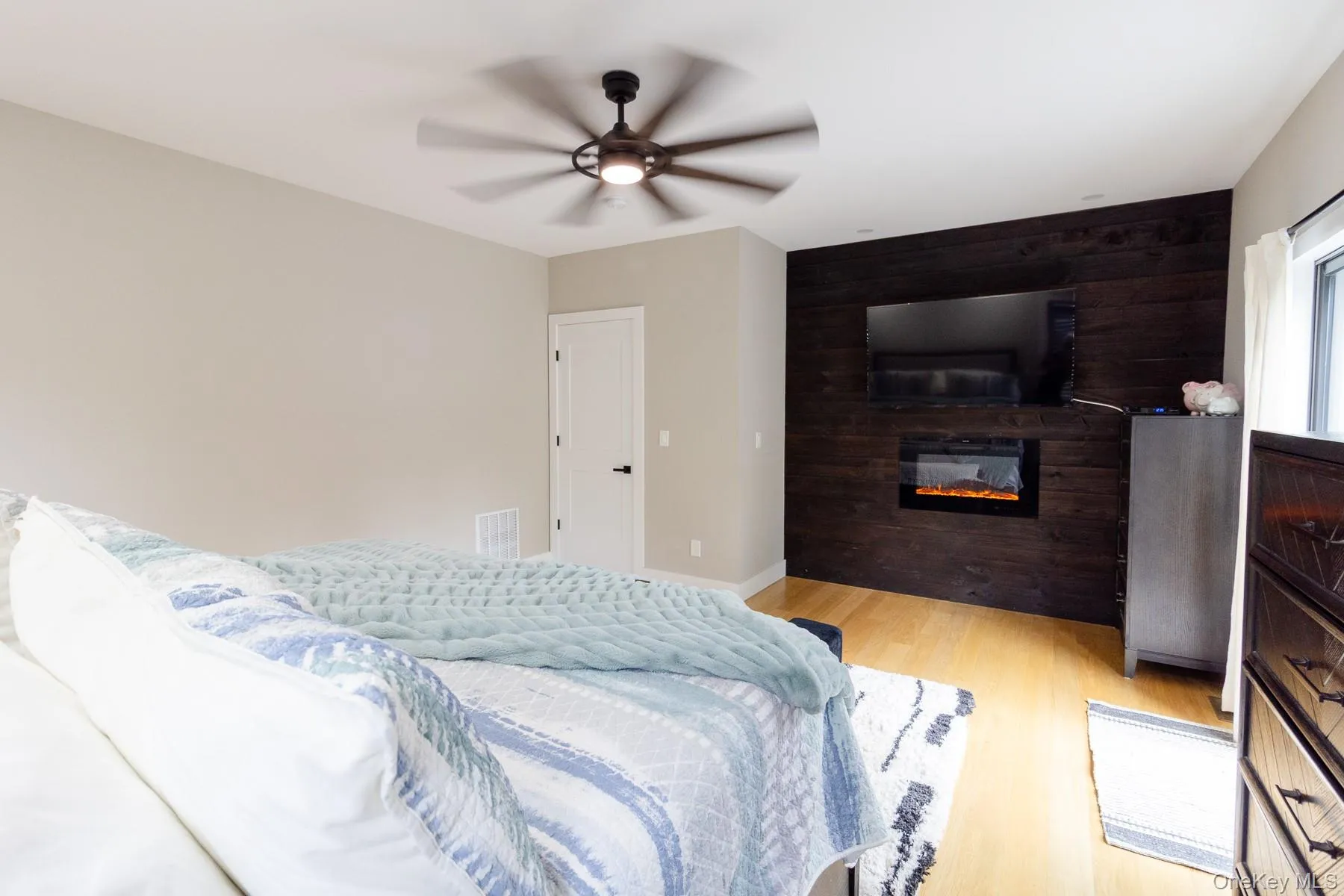 A custom fireplace feature wall adds distinctive character creating a striking focal point within the primary bedroom. A custom fireplace feature wall adds distinctive character creating a striking focal point within the primary bedroom.