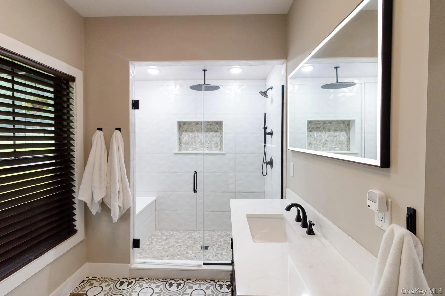 An oversized illuminated mirror enhances the sense of light while the expansive vanity and walk- in shower, complete with built in bench, create a polished, highly functional bath designed for everyday comfort. An oversized illuminated mirror enhances the sense of light while the expansive vanity and walk- in shower, complete with built in bench, create a polished, highly functional bath designed for everyday comfort.