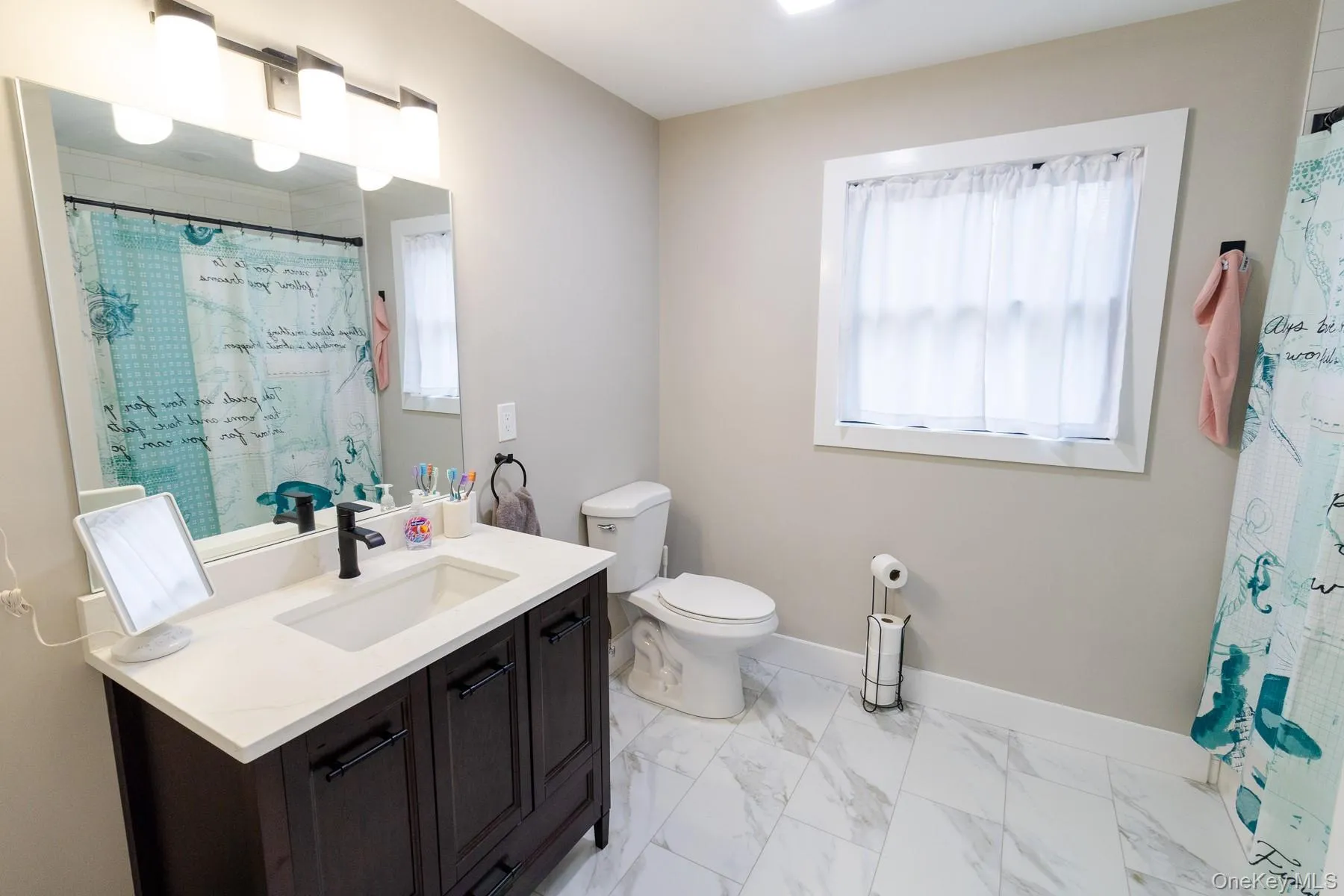 This full bathroom pairs a dark wood vanity with crisp white finishes and abundant natural light for a fresh polished look with timeless appeal. This full bathroom pairs a dark wood vanity with crisp white finishes and abundant natural light for a fresh polished look with timeless appeal.