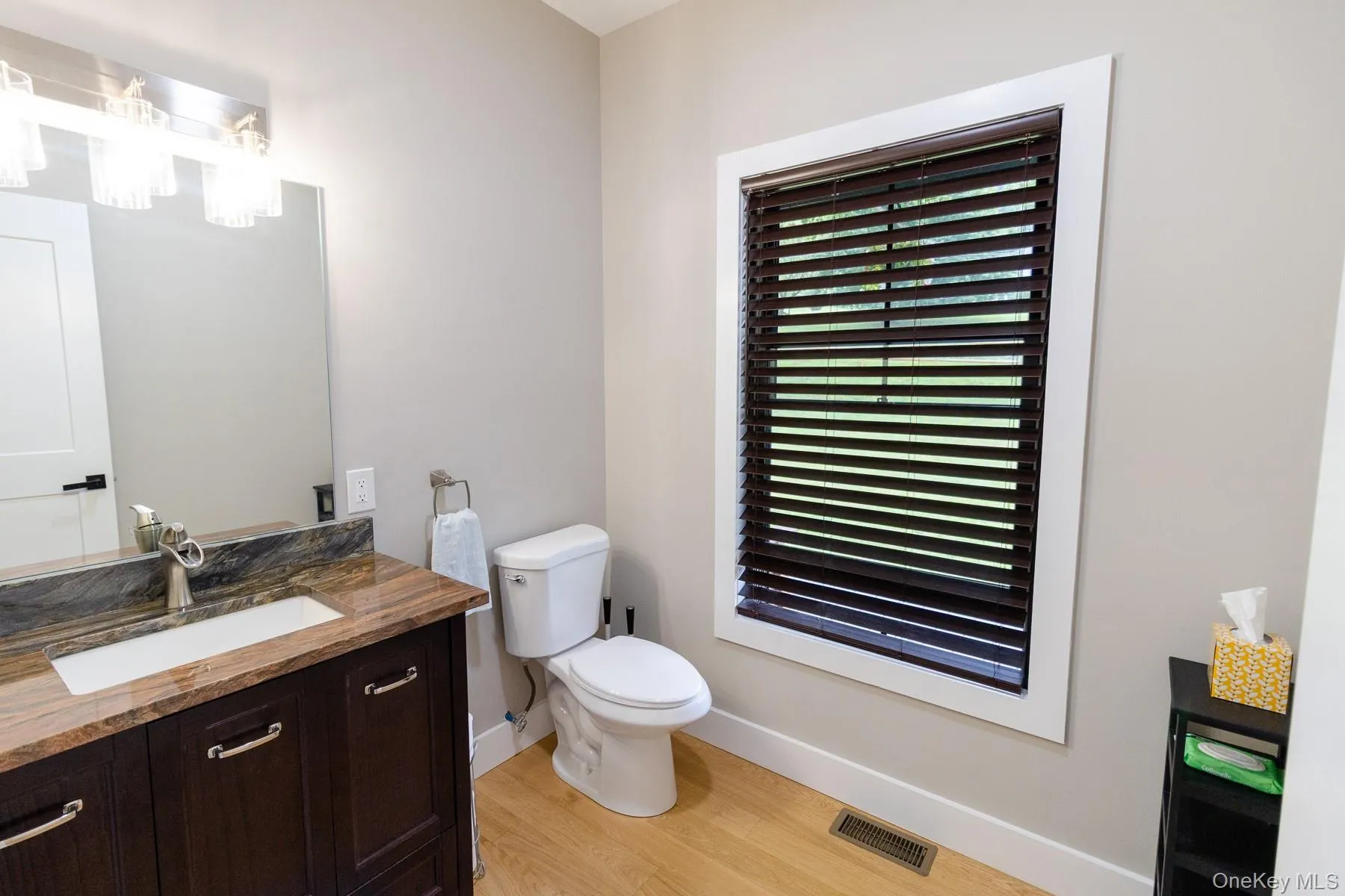 Dark wood cabinetry, a distinctive countertop and an oversized window combine to give this first floor half bath a bright contemporary look. Dark wood cabinetry, a distinctive countertop and an oversized window combine to give this first floor half bath a bright contemporary look.
