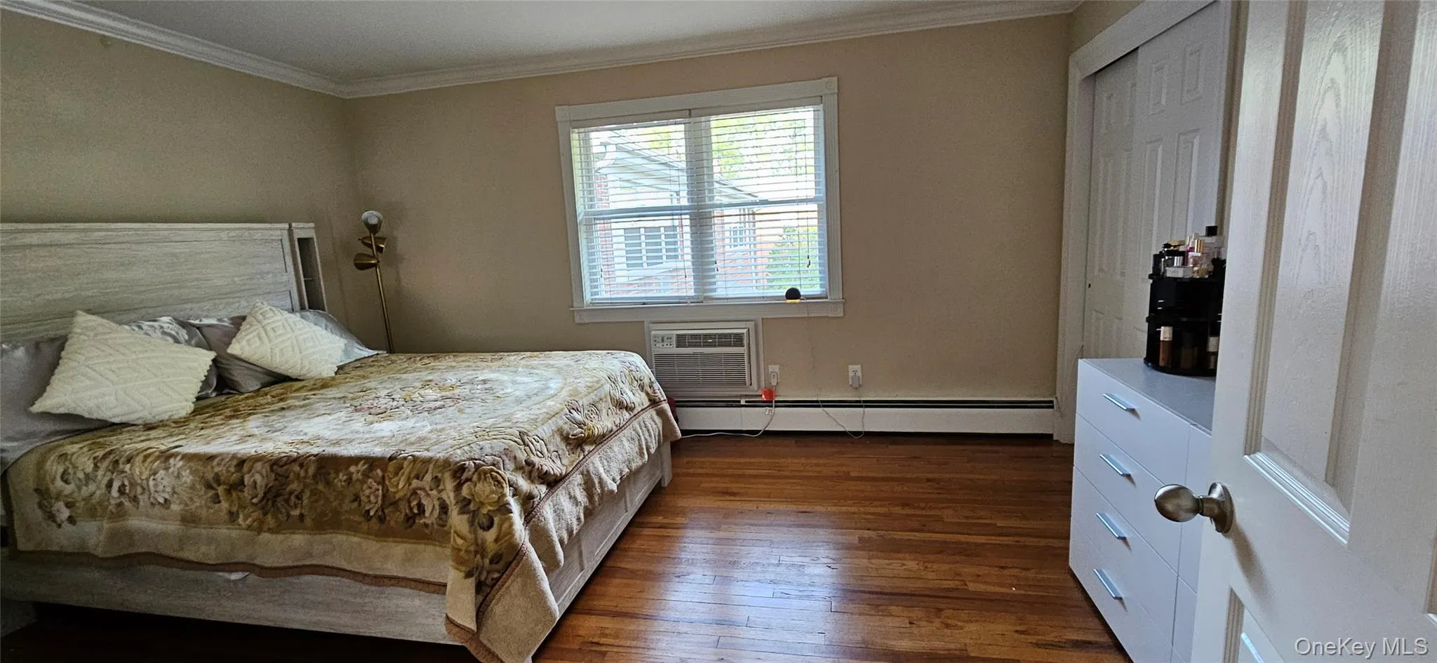 Bedroom with baseboard heating, crown molding, dark wood finished floors, and a wall unit AC Bedroom with baseboard heating, crown molding, dark wood finished floors, and a wall unit AC