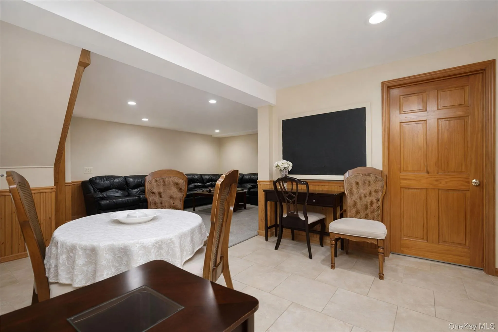 Open concept room featuring recessed lighting, wood paneling, and an interior wood door Open concept room featuring recessed lighting, wood paneling, and an interior wood door