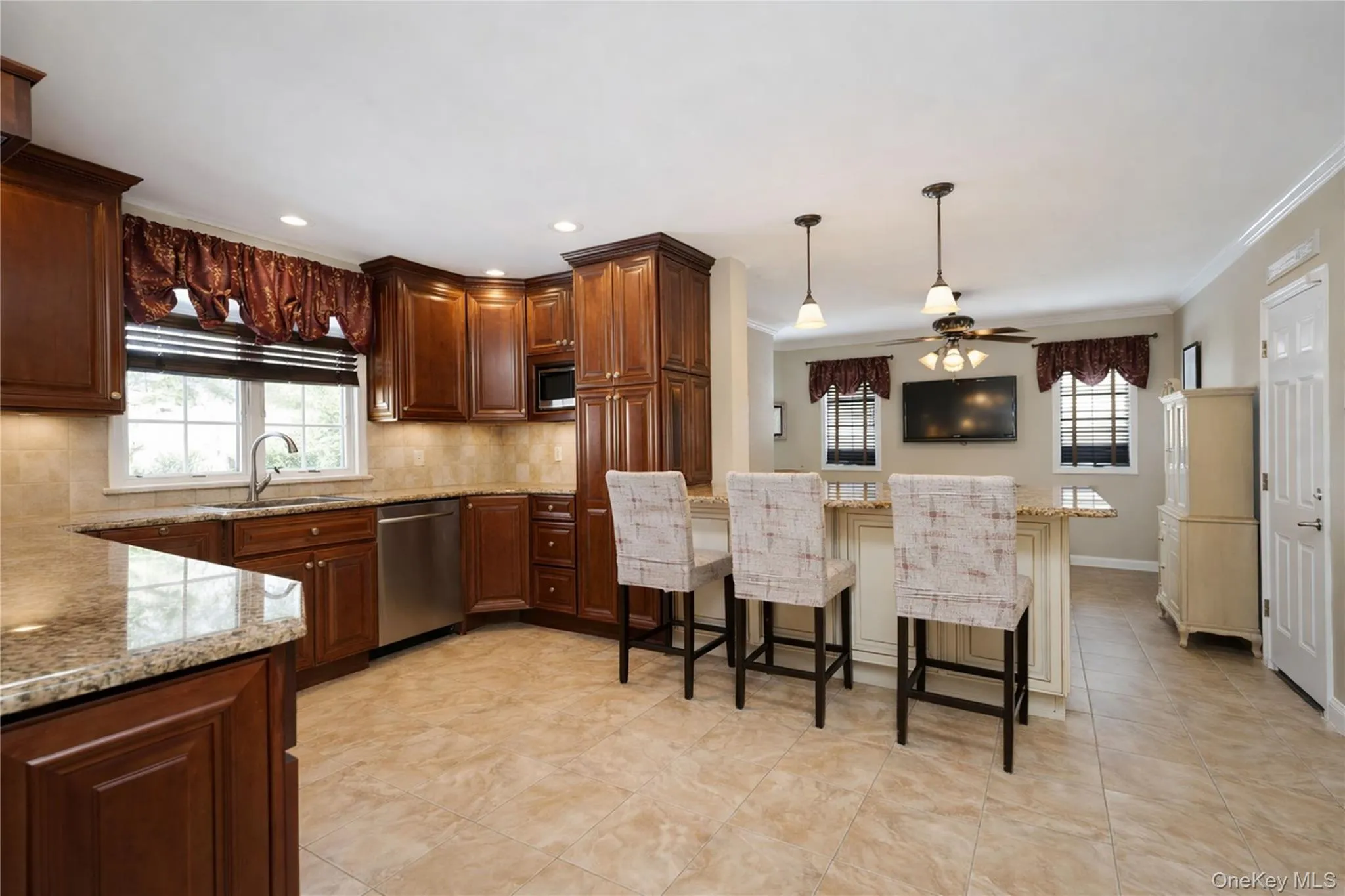 Kitchen featuring wood cabinetry, granite countertops, tile flooring, stainless steel appliances, and a central island with pendant lighting Kitchen featuring wood cabinetry, granite countertops, tile flooring, stainless steel appliances, and a central island with pendant lighting