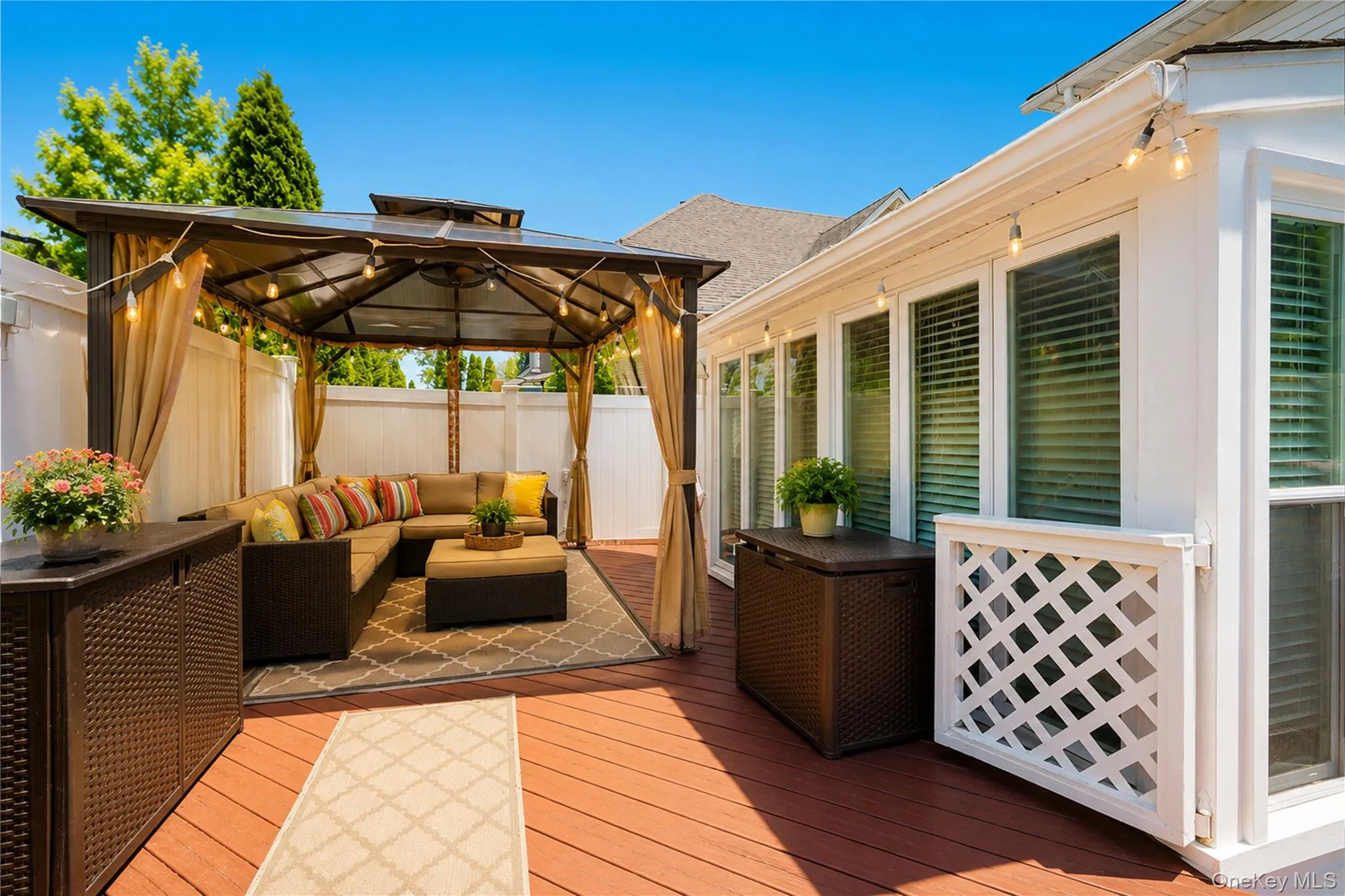 Spacious outdoor deck featuring a gazebo with drapes, string lighting, and multiple windows along the home's exterior Spacious outdoor deck featuring a gazebo with drapes, string lighting, and multiple windows along the home's exterior