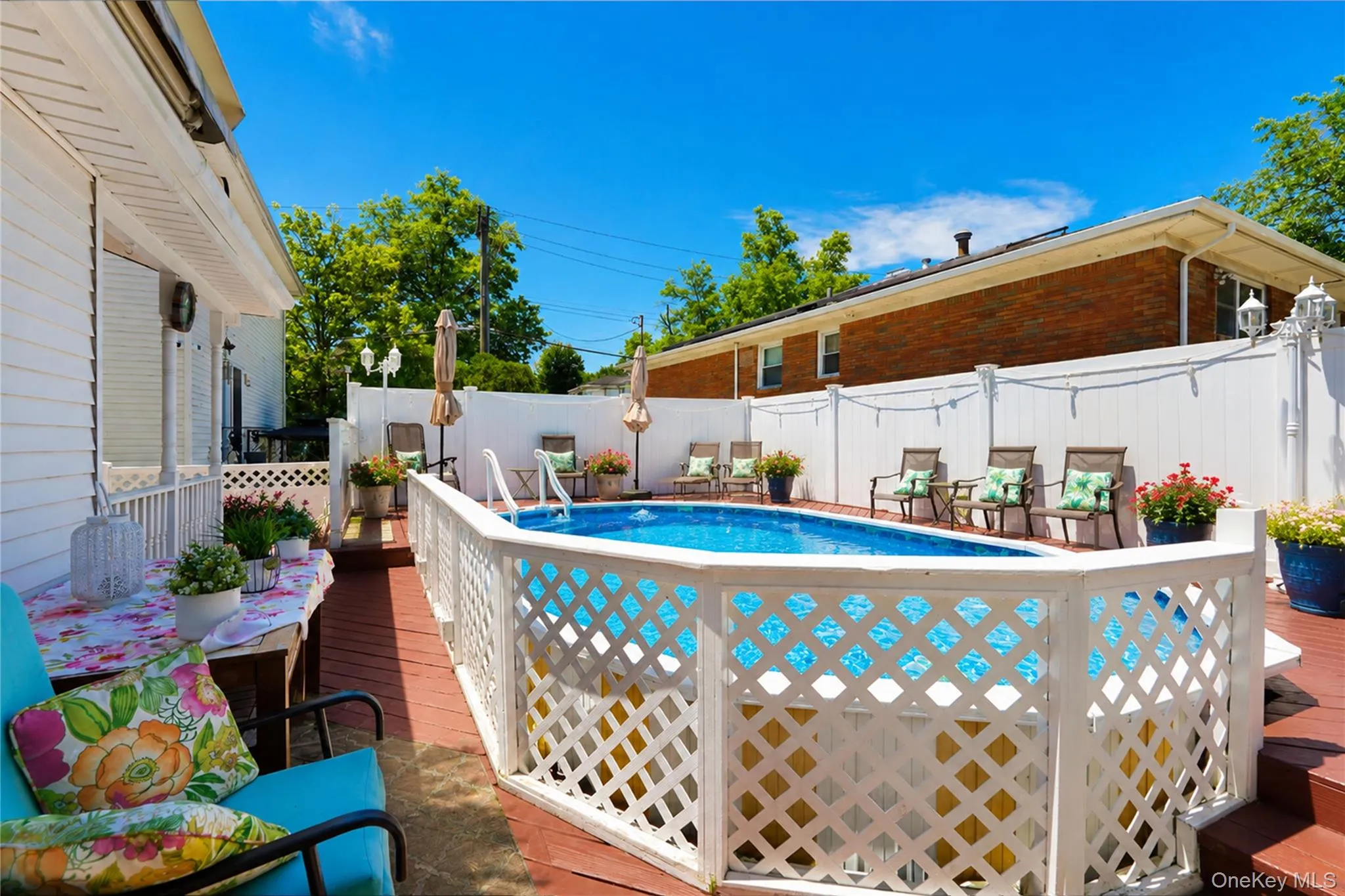Above-ground pool surrounded by a white lattice fence and a red-stained wood-finish deck Above-ground pool surrounded by a white lattice fence and a red-stained wood-finish deck