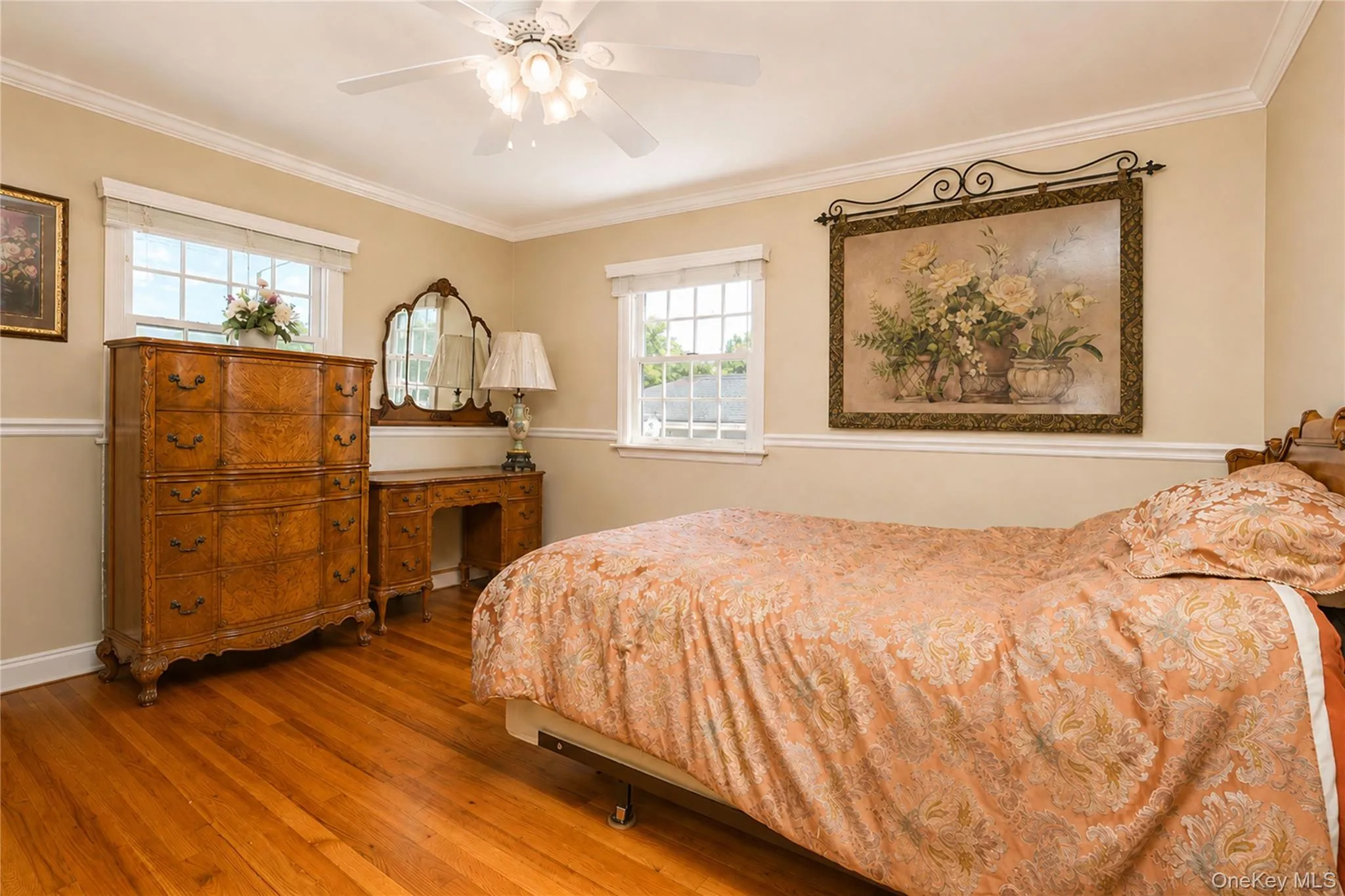 Hardwood flooring throughout this room, featuring two windows, crown molding, and a ceiling fan with integrated lighting Hardwood flooring throughout this room, featuring two windows, crown molding, and a ceiling fan with integrated lighting