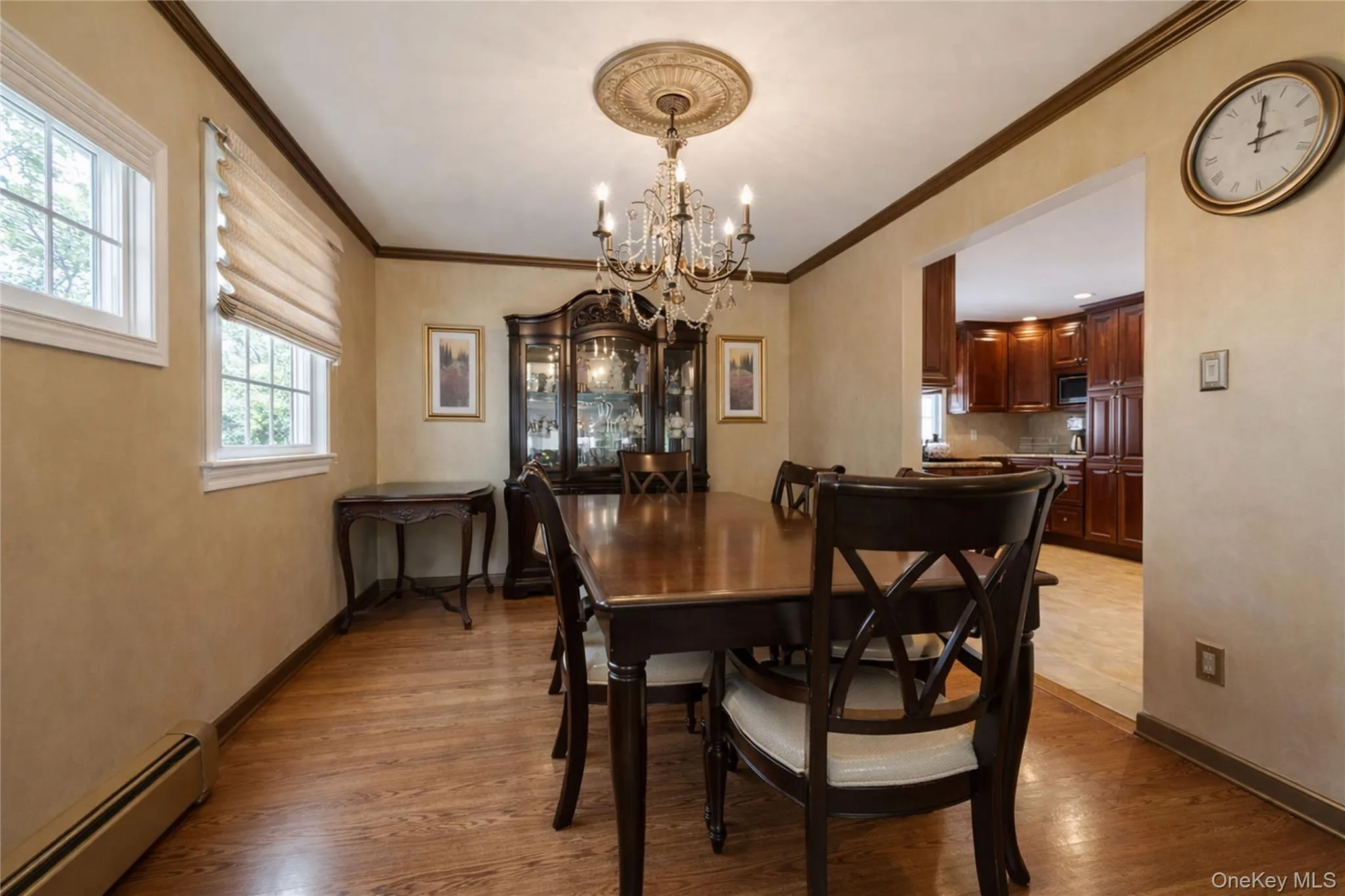 Formal dining area featuring wood-finish flooring, two large windows, a decorative chandelier, and crown molding Formal dining area featuring wood-finish flooring, two large windows, a decorative chandelier, and crown molding