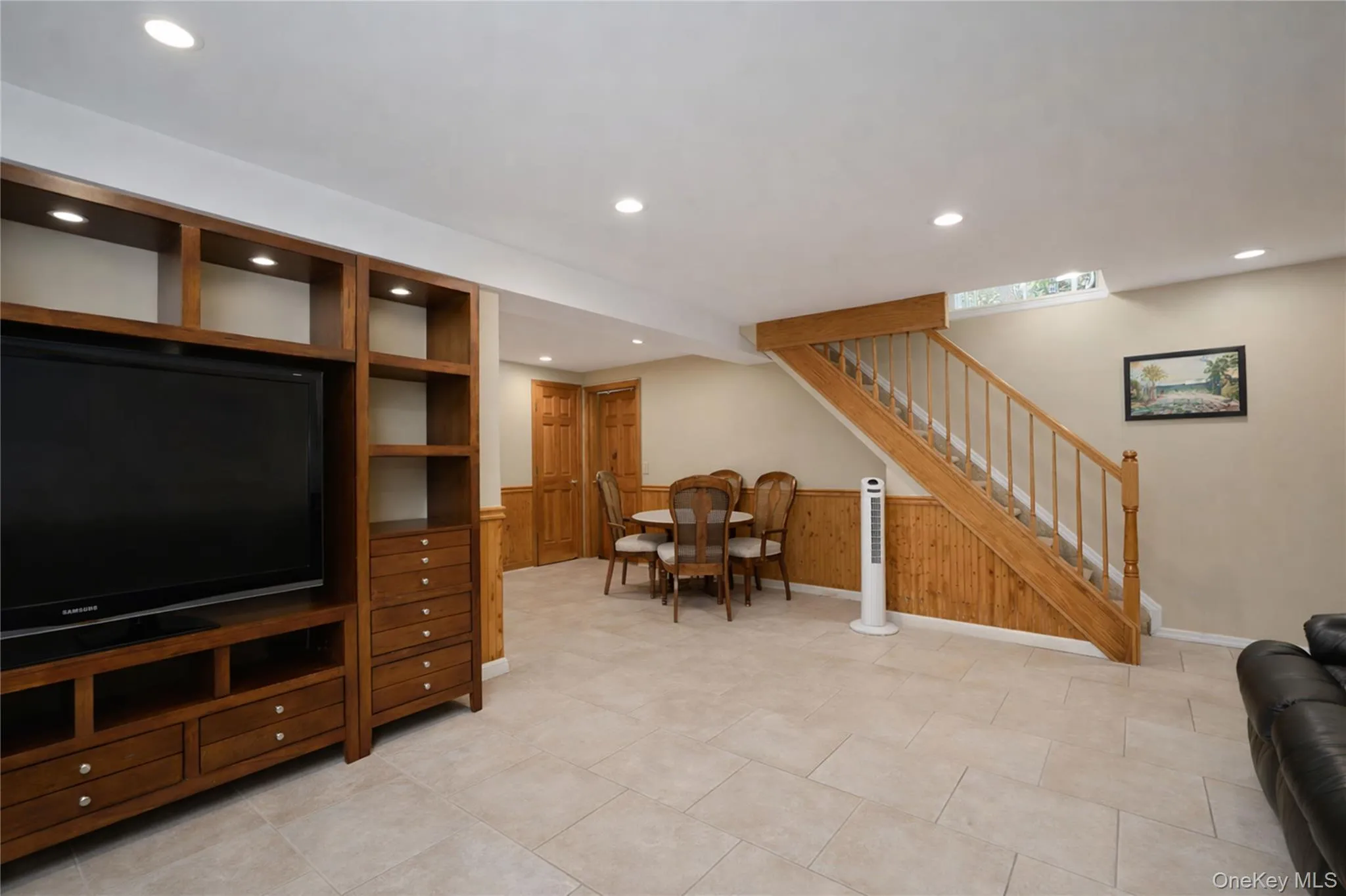 Expansive room featuring recessed lighting, tile flooring, and a built-in media center with integrated shelving and drawers Expansive room featuring recessed lighting, tile flooring, and a built-in media center with integrated shelving and drawers
