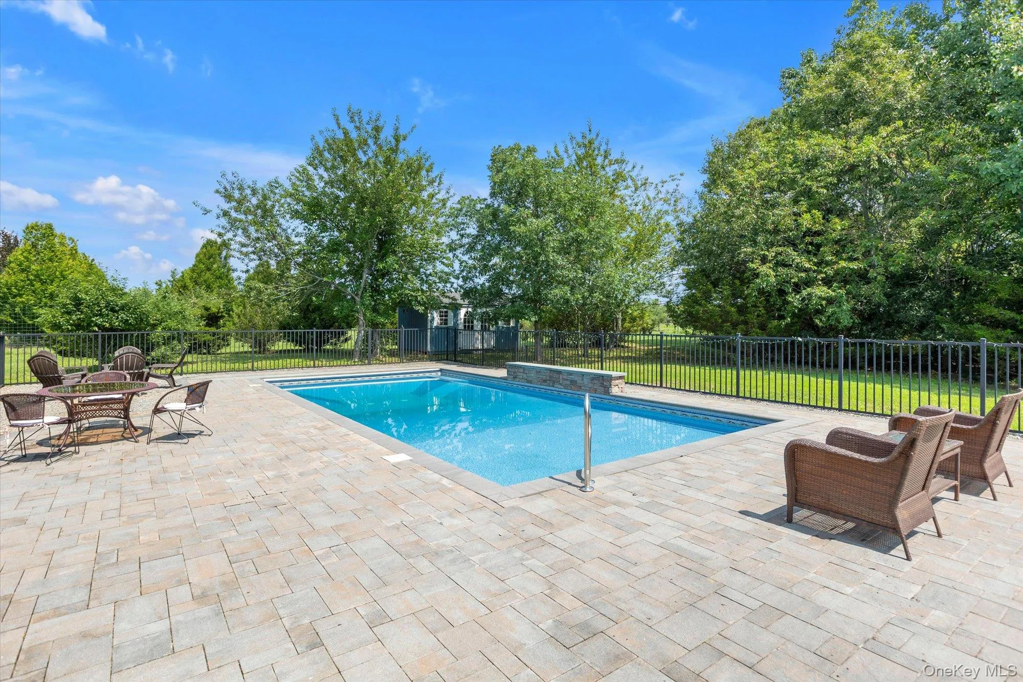 Outdoor pool area featuring a rectangular pool, paver patio, black metal fencing, Outdoor pool area featuring a rectangular pool, paver patio, black metal fencing,