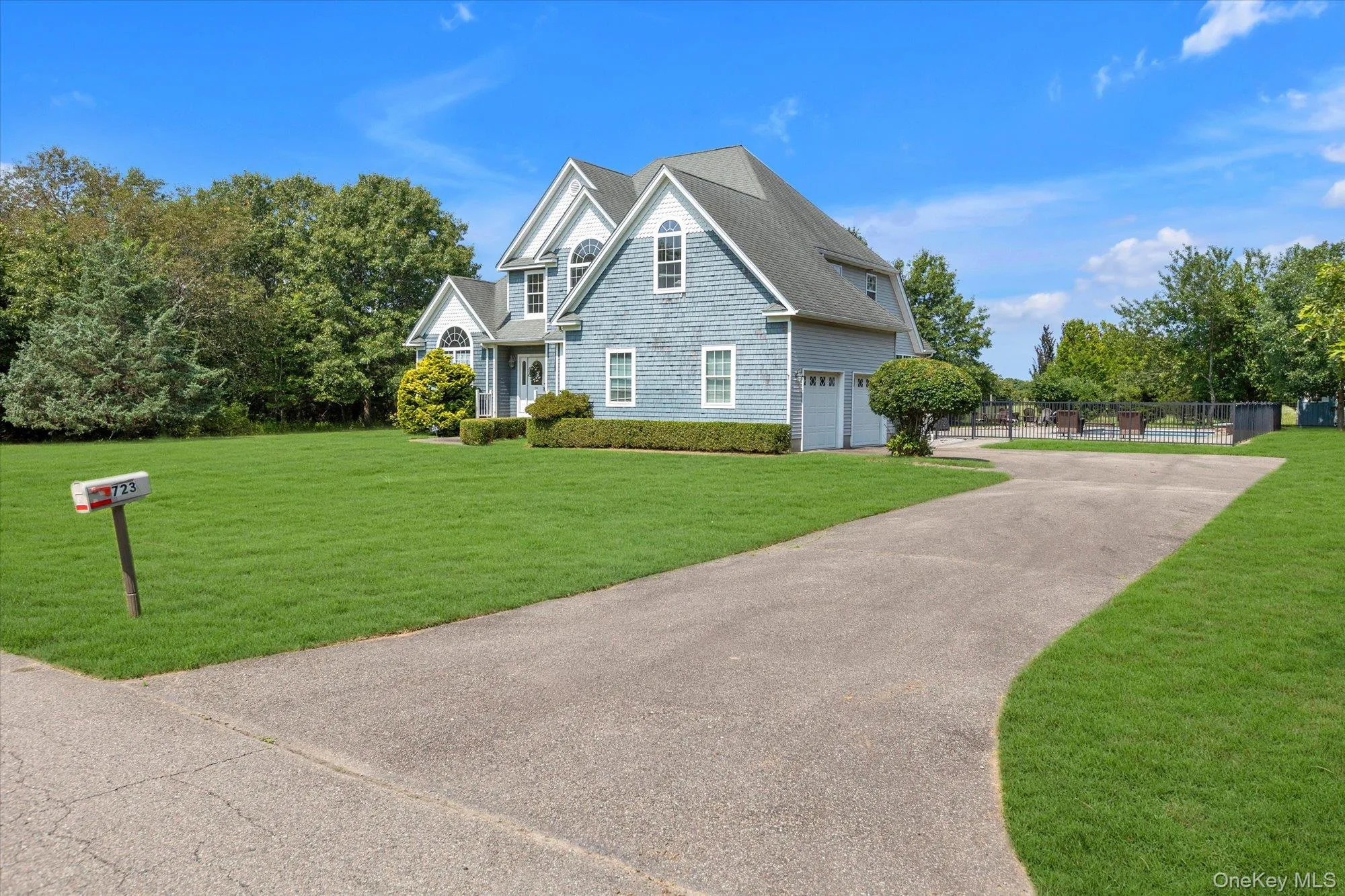 Shingle-sided exterior with multiple gables, an attached two-car garage, a paved driveway, and a spacious lawn Shingle-sided exterior with multiple gables, an attached two-car garage, a paved driveway, and a spacious lawn
