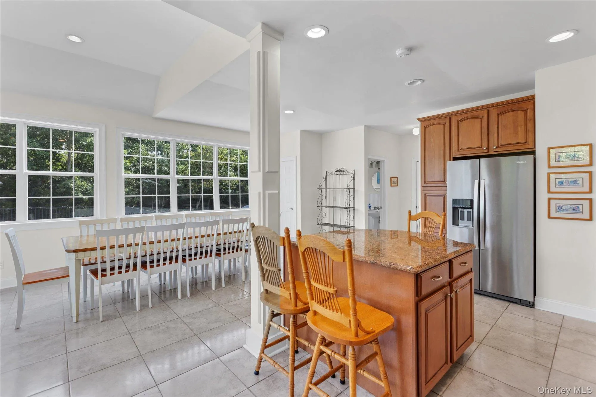 Kitchen with wood cabinetry, stainless steel refrigerator, and a granite-topped island Kitchen with wood cabinetry, stainless steel refrigerator, and a granite-topped island