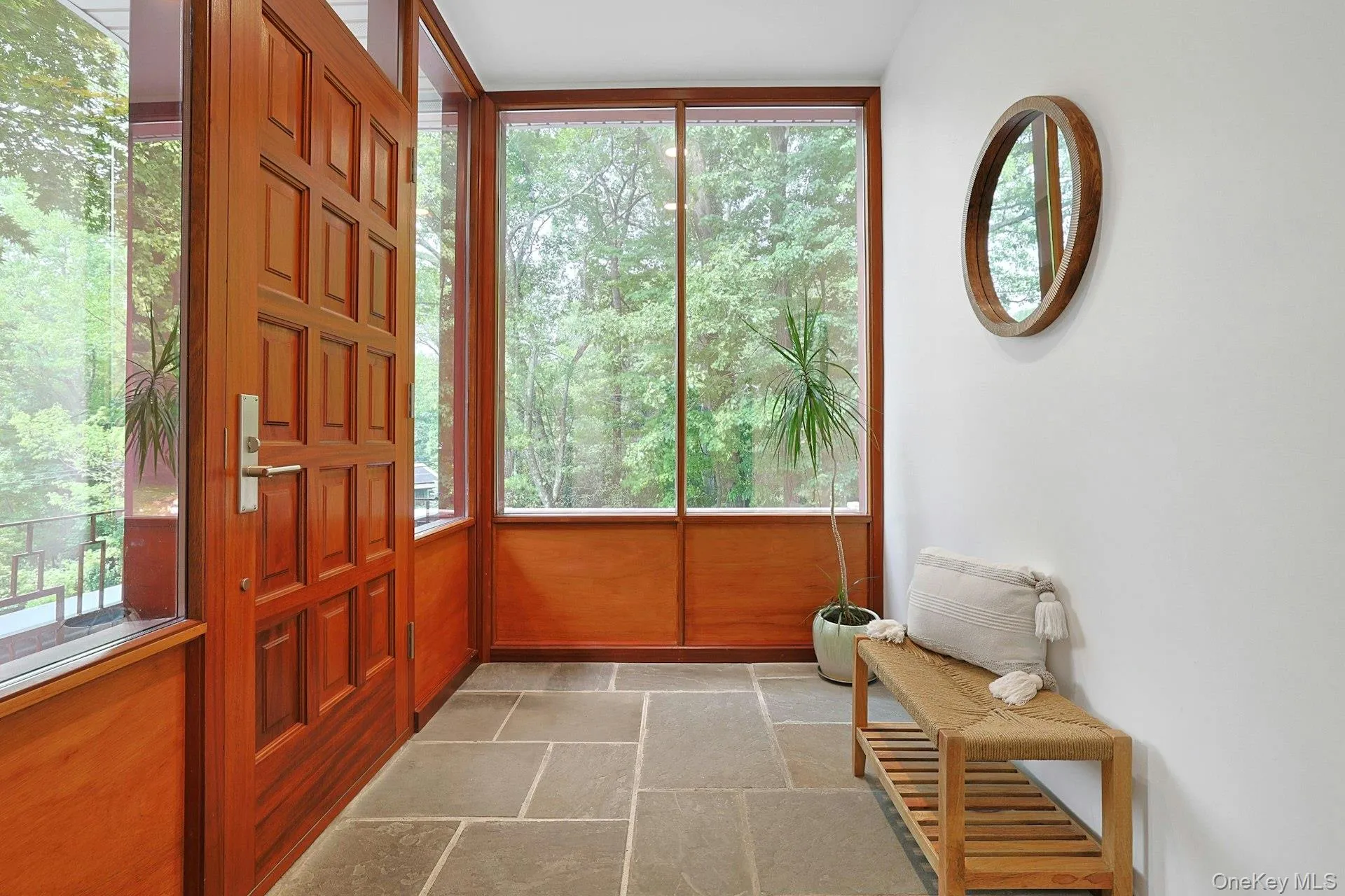 The inviting foyer features radiant-heated bluestone flooring, rich mahogany detailing, and oversized windows that flood the space with natural light. The inviting foyer features radiant-heated bluestone flooring, rich mahogany detailing, and oversized windows that flood the space with natural light.