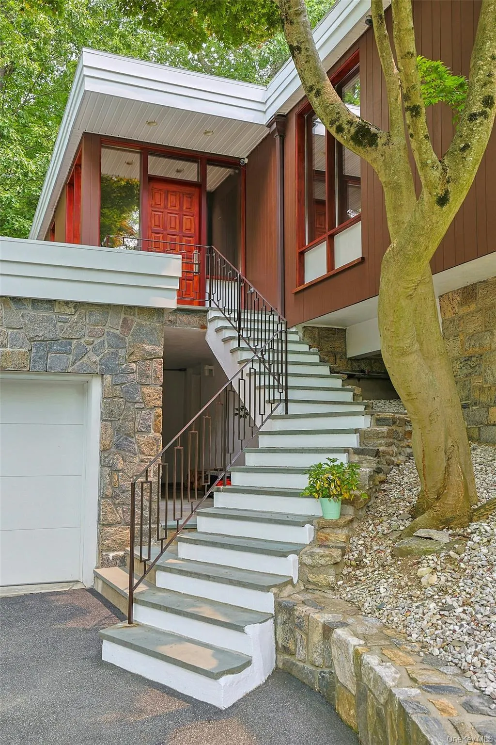 A contemporary stairway with a snowmelt feature leads to the welcoming front porch and impressive custom solid mahogany entry door, setting the tone for the home's timeless design. A contemporary stairway with a snowmelt feature leads to the welcoming front porch and impressive custom solid mahogany entry door, setting the tone for the home's timeless design.