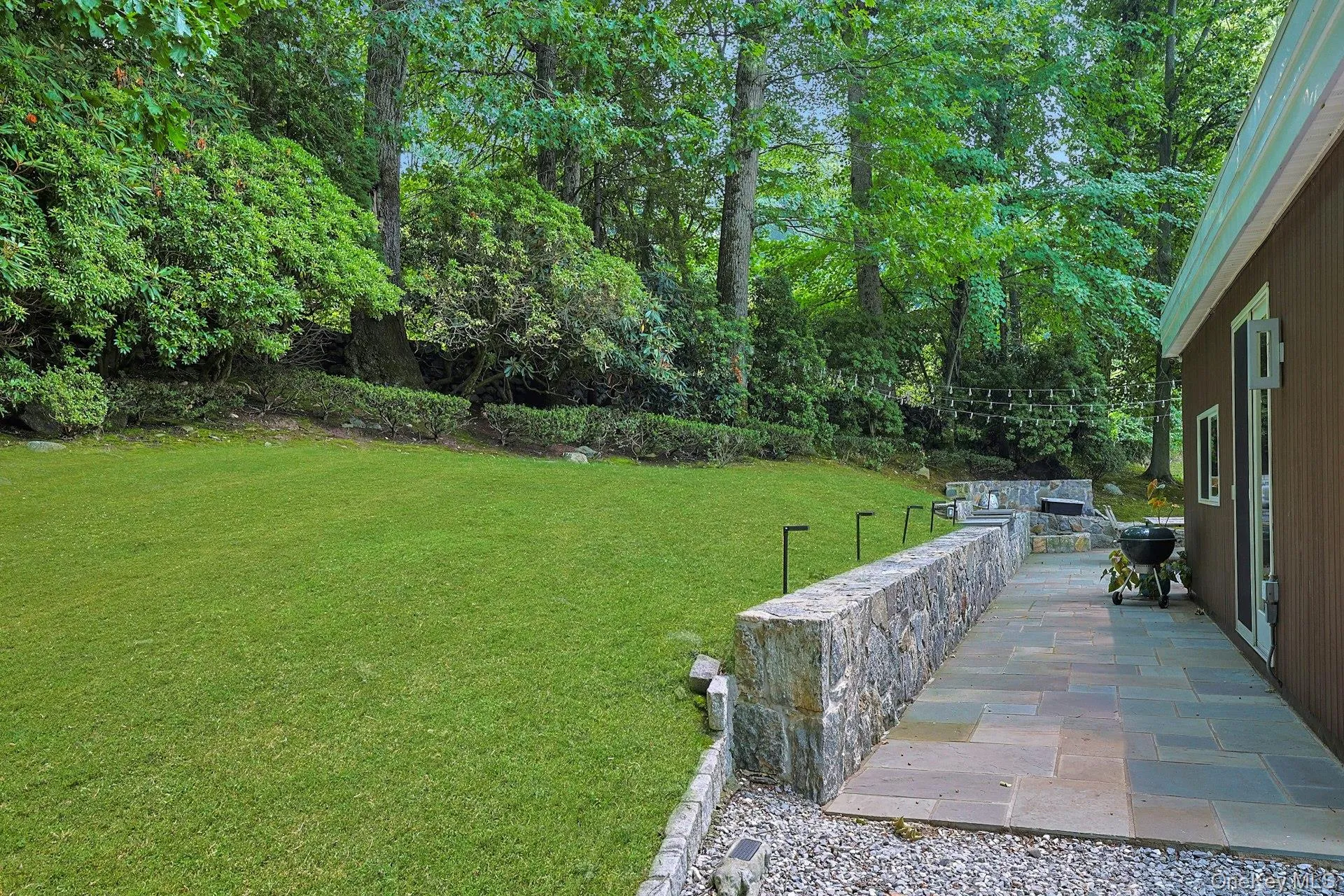 A stunning lawn bordered by mature trees and handsome stacked stone retaining walls provides an ideal backdrop for recreation, gardening, or relaxing outdoors. A stunning lawn bordered by mature trees and handsome stacked stone retaining walls provides an ideal backdrop for recreation, gardening, or relaxing outdoors.