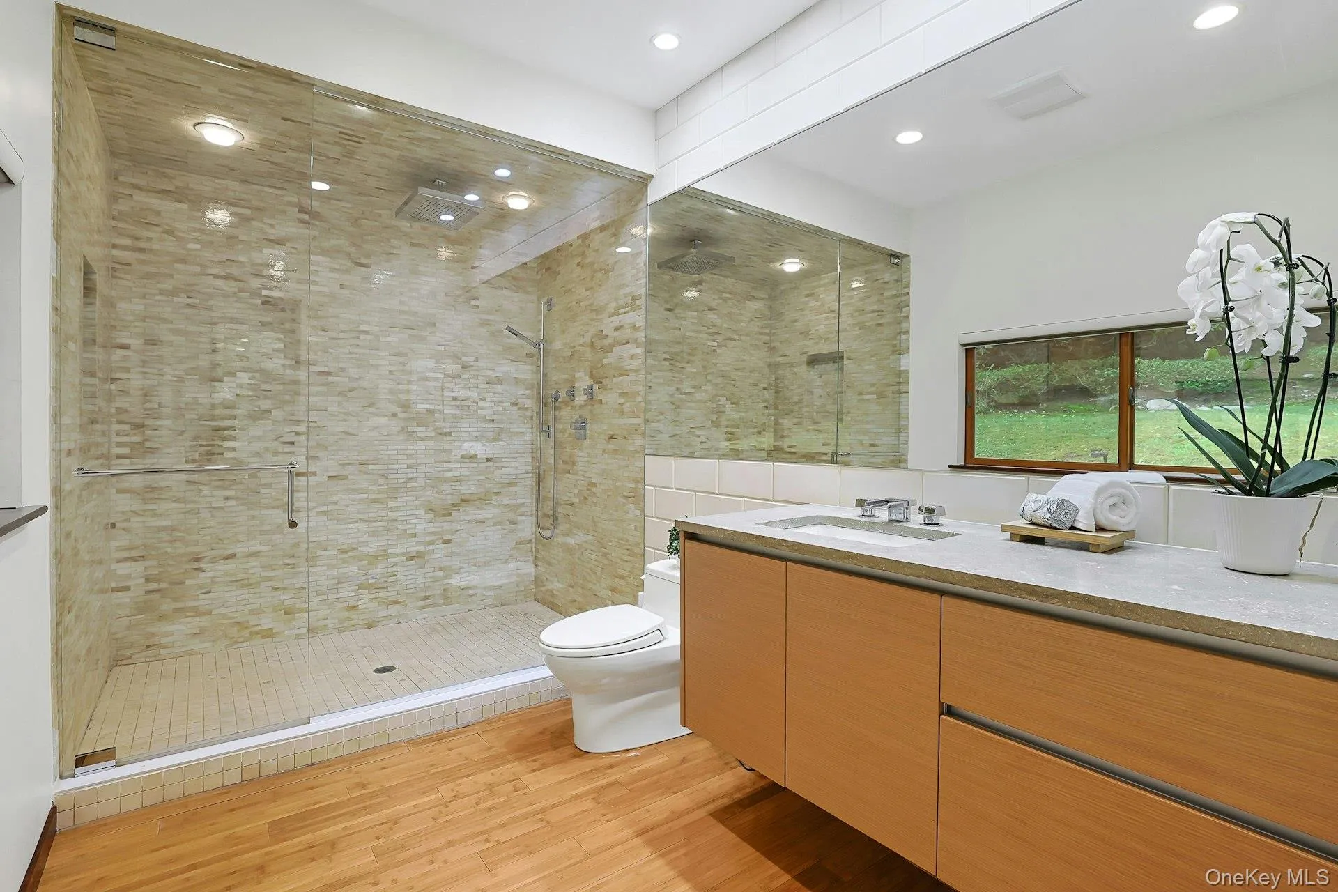 The luxurious primary bath features radiant heated floors, a Polyform vanity with limestone countertop, and an oversized walk-in shower with dual shower heads. The luxurious primary bath features radiant heated floors, a Polyform vanity with limestone countertop, and an oversized walk-in shower with dual shower heads.