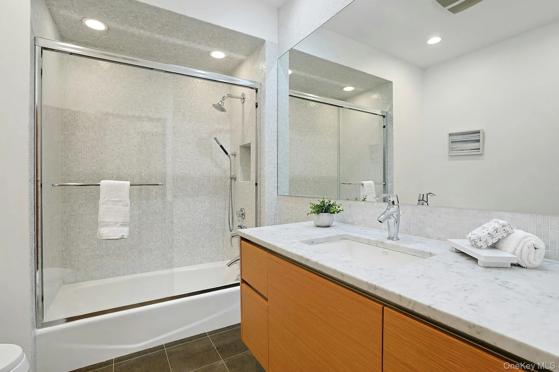 Beautifully renovated hall bath featuring elegant glass tile, Waterworks fixtures, a Polyform vanity, and timeless contemporary finishes. Beautifully renovated hall bath featuring elegant glass tile, Waterworks fixtures, a Polyform vanity, and timeless contemporary finishes.