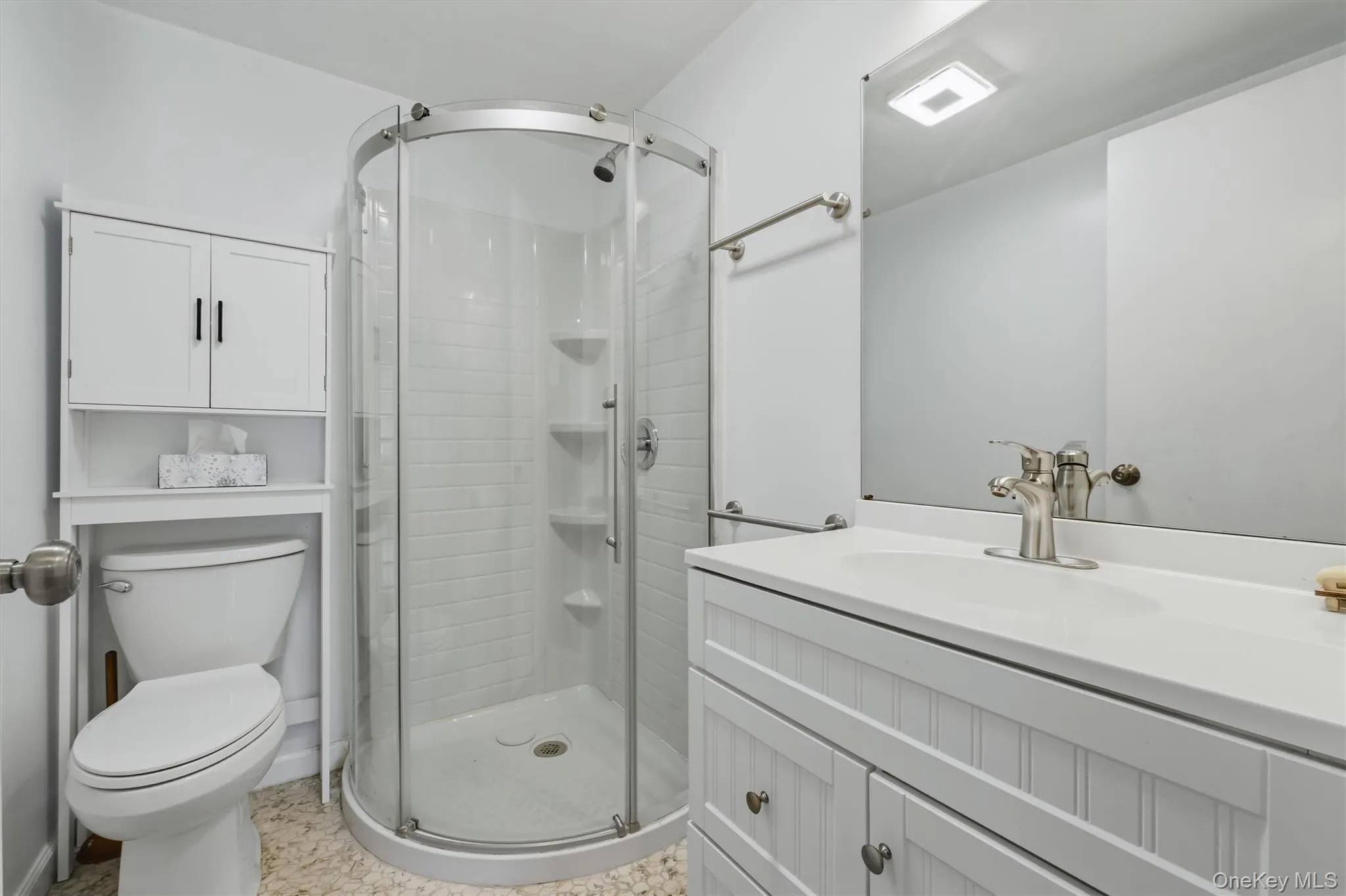 Full bathroom featuring a curved glass shower enclosure, white subway tile shower surround, and a white vanity with beadboard paneling Full bathroom featuring a curved glass shower enclosure, white subway tile shower surround, and a white vanity with beadboard paneling
