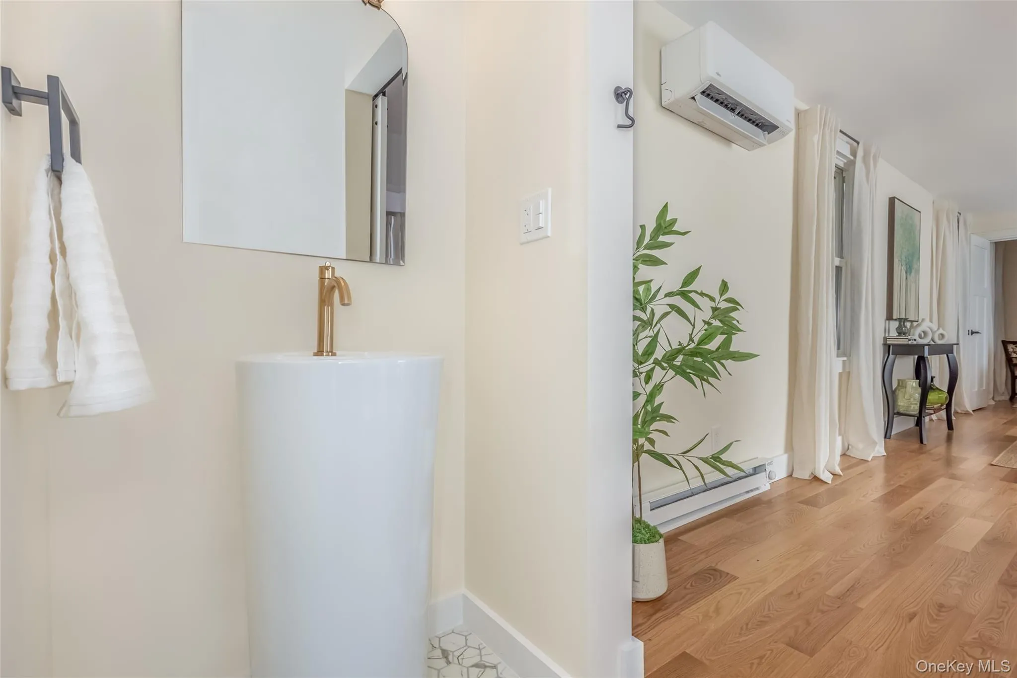 Hallway with light wood-type flooring, an AC wall unit, and a baseboard heating unit Hallway with light wood-type flooring, an AC wall unit, and a baseboard heating unit