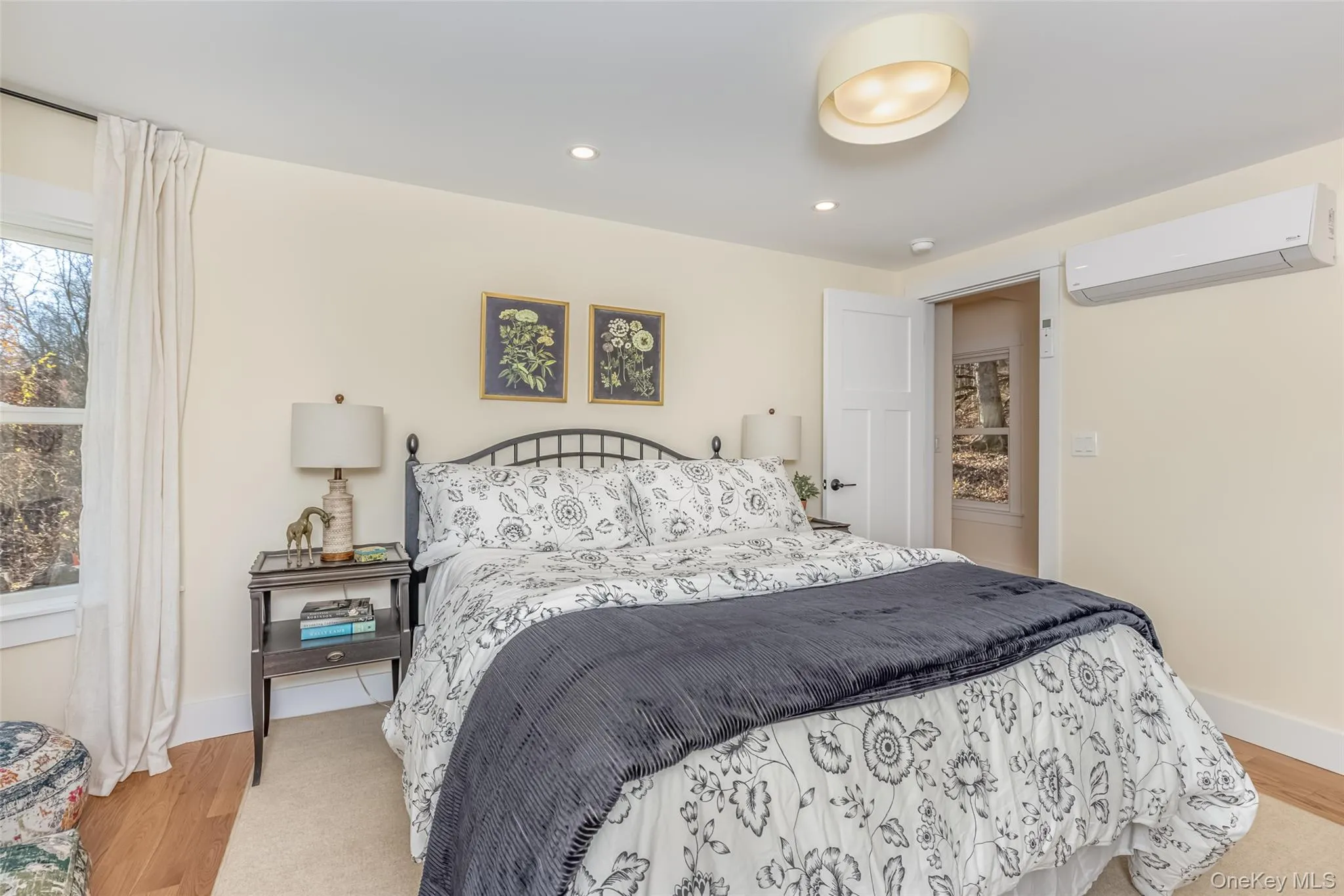 Bedroom featuring light wood-type flooring and an AC wall unit Bedroom featuring light wood-type flooring and an AC wall unit