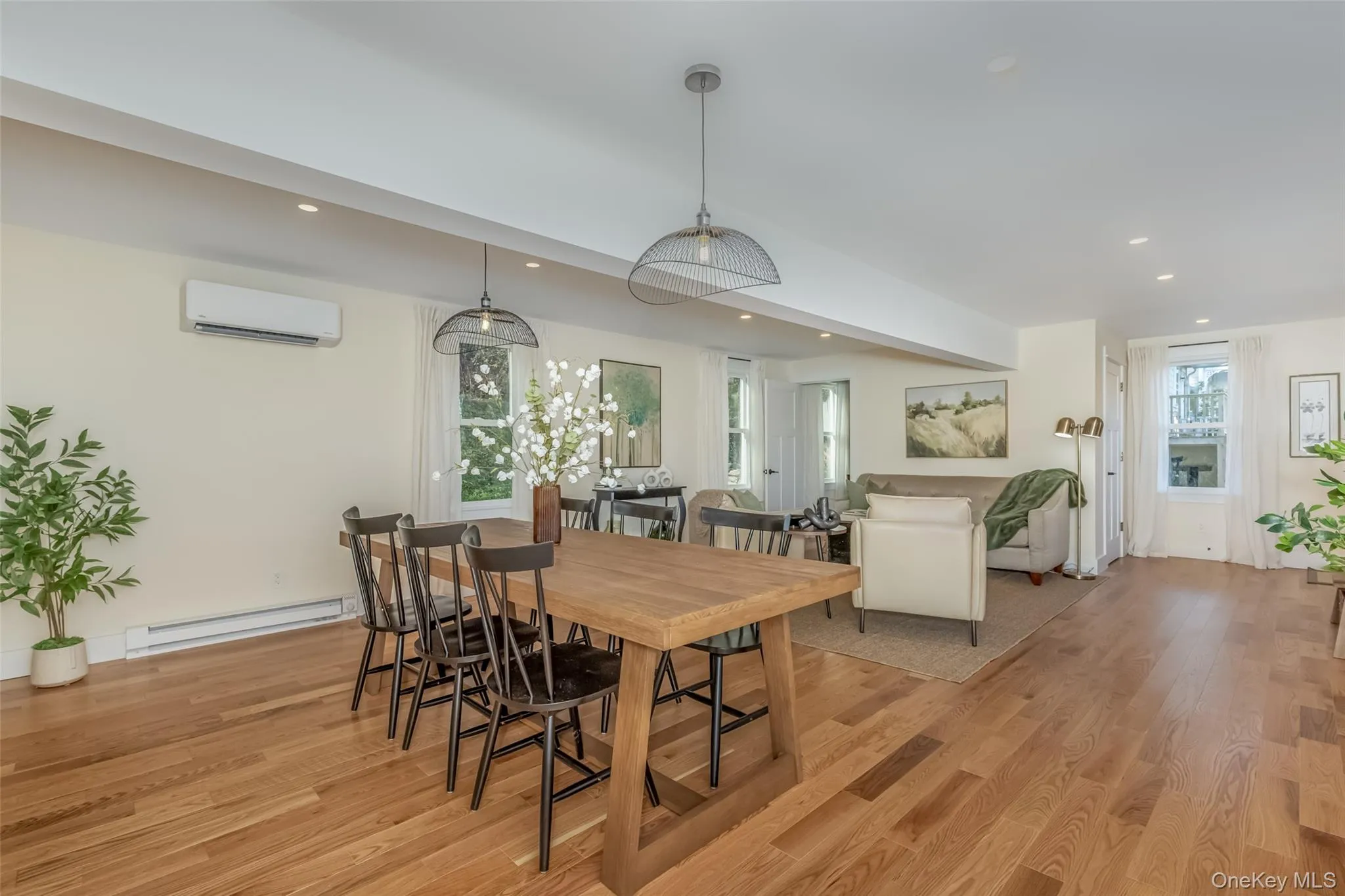 Dining room featuring a wall mounted AC, light wood-type flooring, and baseboard heating Dining room featuring a wall mounted AC, light wood-type flooring, and baseboard heating