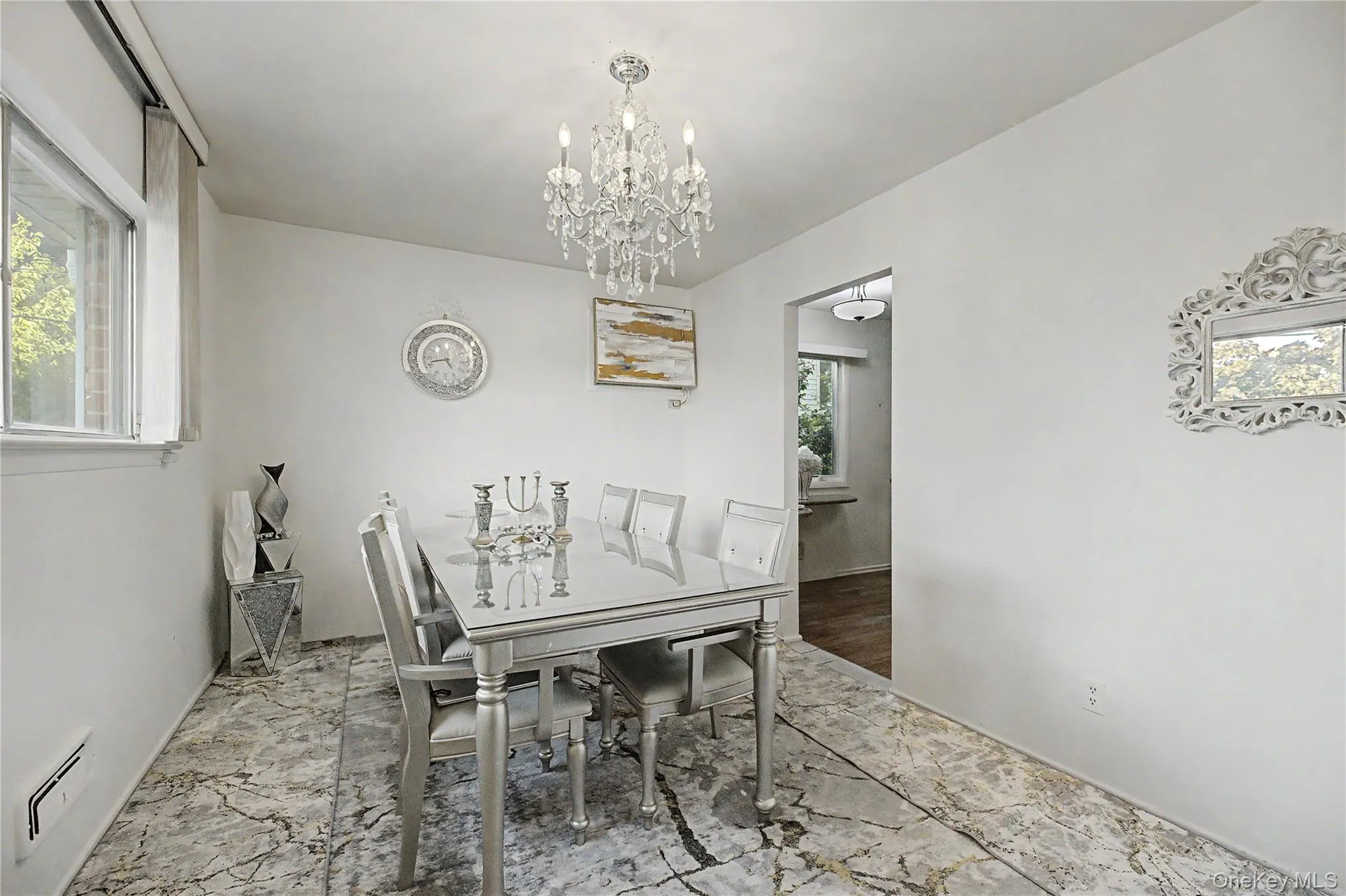 Dining area featuring a chandelier light fixture, white walls, and a patterned tile floor Dining area featuring a chandelier light fixture, white walls, and a patterned tile floor
