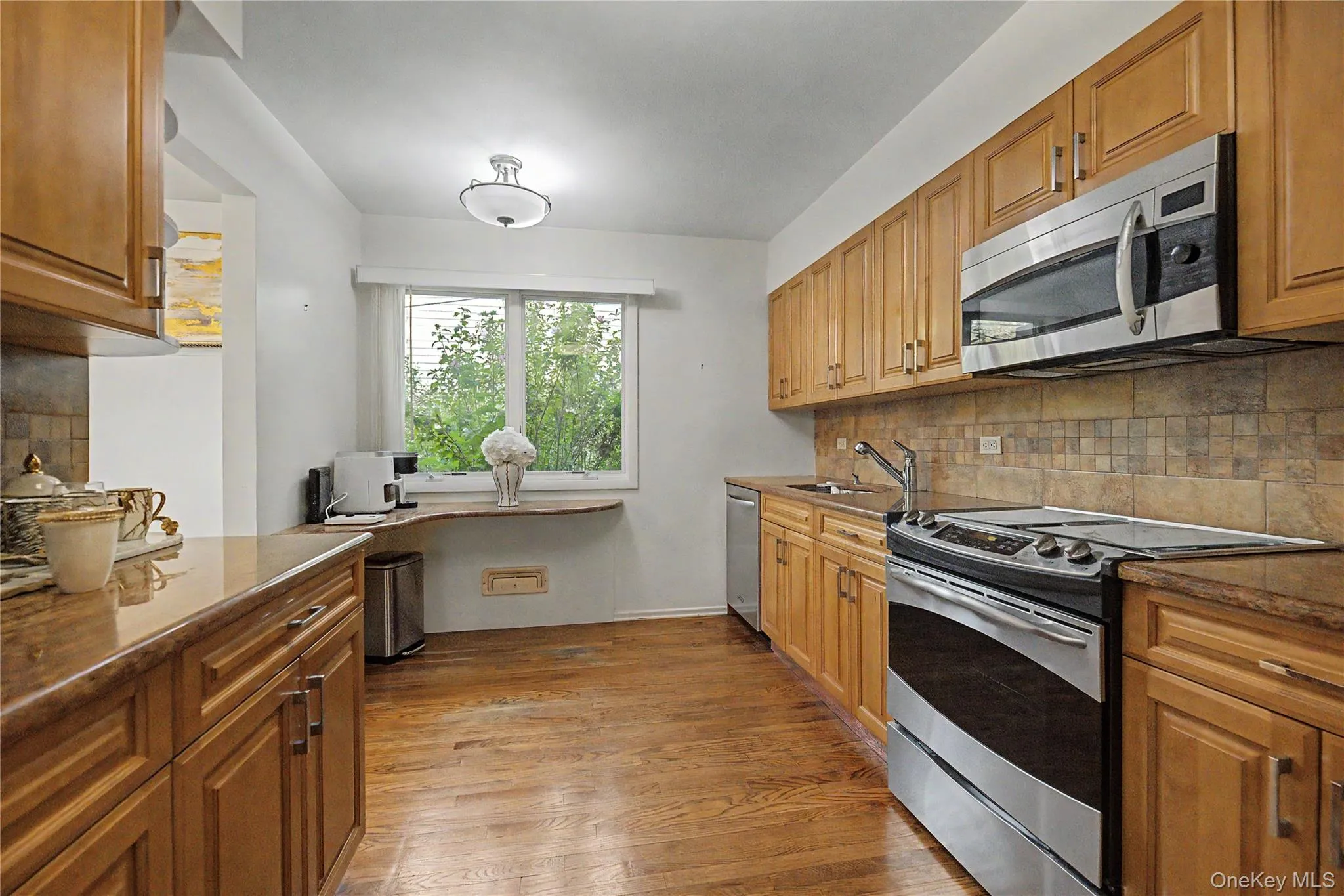 Full kitchen featuring wood-finish cabinetry, stainless steel appliances, stone-finish countertops, and tile backsplash Full kitchen featuring wood-finish cabinetry, stainless steel appliances, stone-finish countertops, and tile backsplash