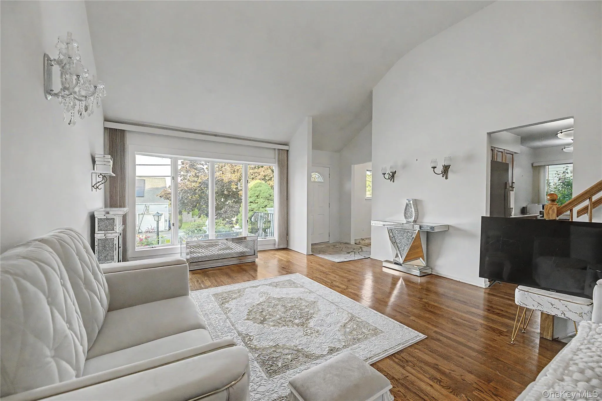 Spacious living area featuring high vaulted ceilings, wood-finish flooring, and large sliding glass doors Spacious living area featuring high vaulted ceilings, wood-finish flooring, and large sliding glass doors