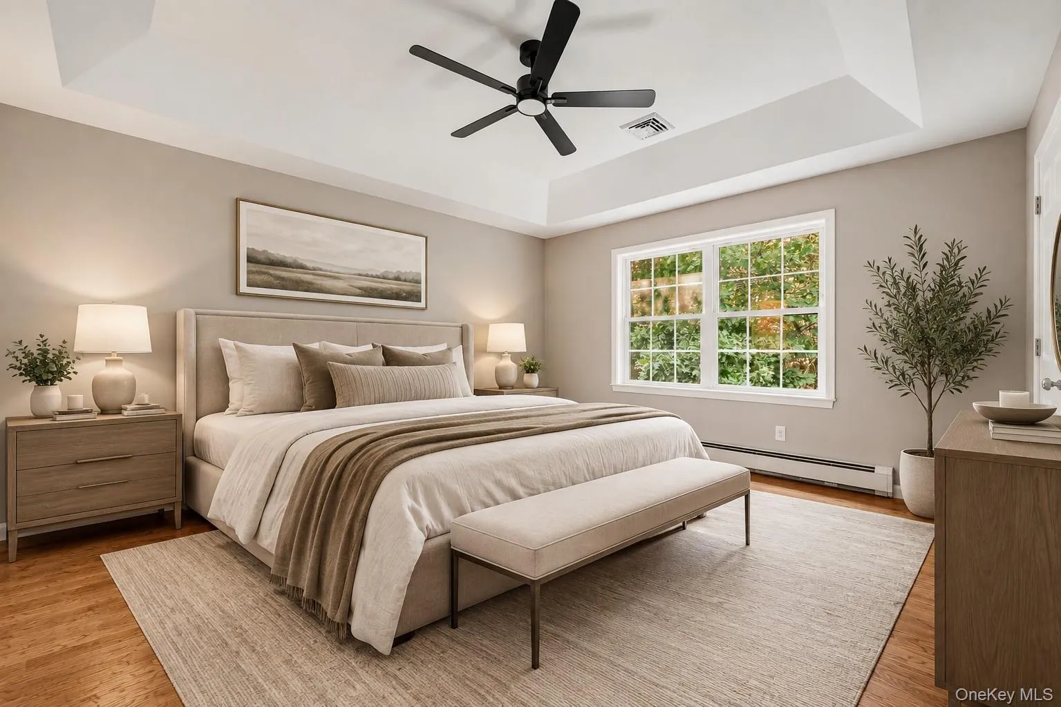 Bedroom staged with furniture. Hardwood Floors and Tray ceiling with large ceiling fan. Bedroom staged with furniture. Hardwood Floors and Tray ceiling with large ceiling fan.