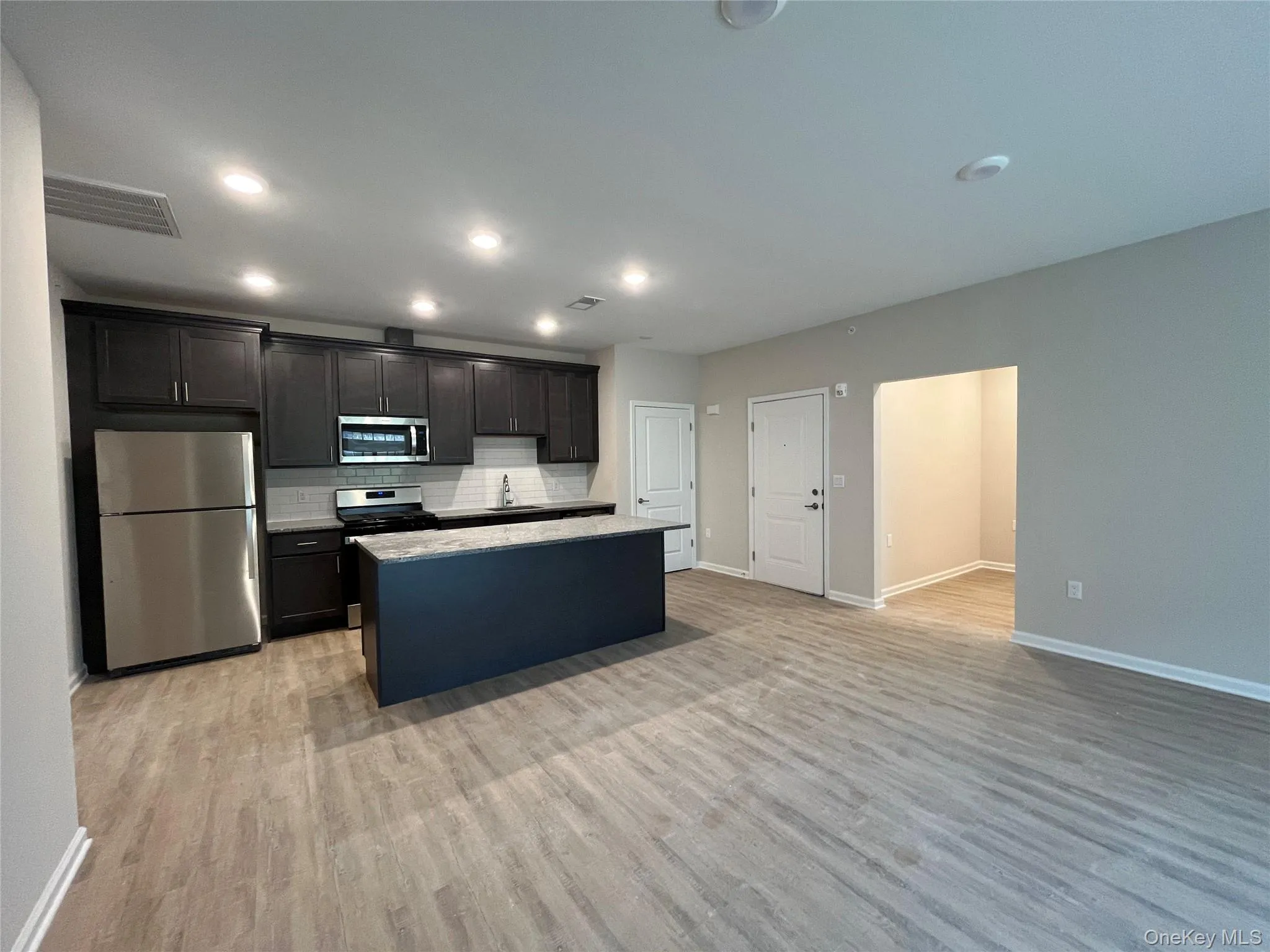The heart of the home—an expansive open-concept great room featuring a chef-inspired kitchen with a large center island, premium stainless steel appliances, contemporary cabinetry, and luxury plank flooring. Bright, airy, and ideal for modern living. The heart of the home—an expansive open-concept great room featuring a chef-inspired kitchen with a large center island, premium stainless steel appliances, contemporary cabinetry, and luxury plank flooring. Bright, airy, and ideal for modern living.