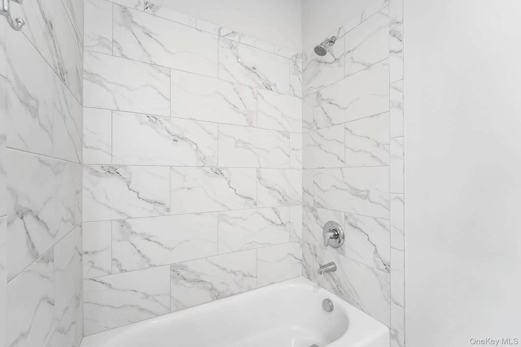 Luxury bath featuring a Kohler® 60-inch low-threshold bathtub for easier entry and exit, marble-look porcelain tile, and contemporary finishes. Luxury bath featuring a Kohler® 60-inch low-threshold bathtub for easier entry and exit, marble-look porcelain tile, and contemporary finishes.