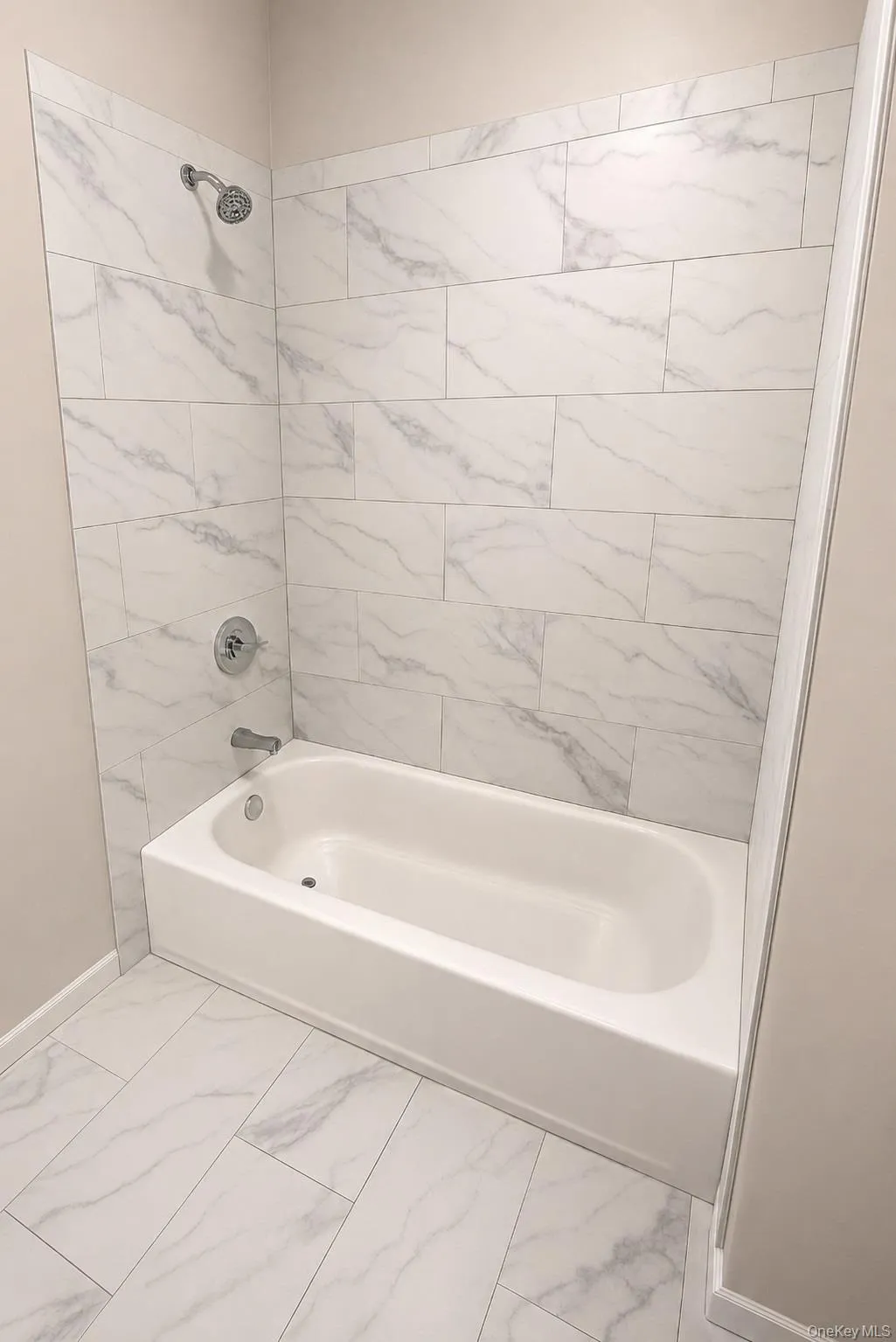 Second bathroom features a low-wall tub for easier entry and exit, surrounded by large-format Calacatta marble-look porcelain tile with coordinating tile flooring and Kohler fixtures. Second bathroom features a low-wall tub for easier entry and exit, surrounded by large-format Calacatta marble-look porcelain tile with coordinating tile flooring and Kohler fixtures.