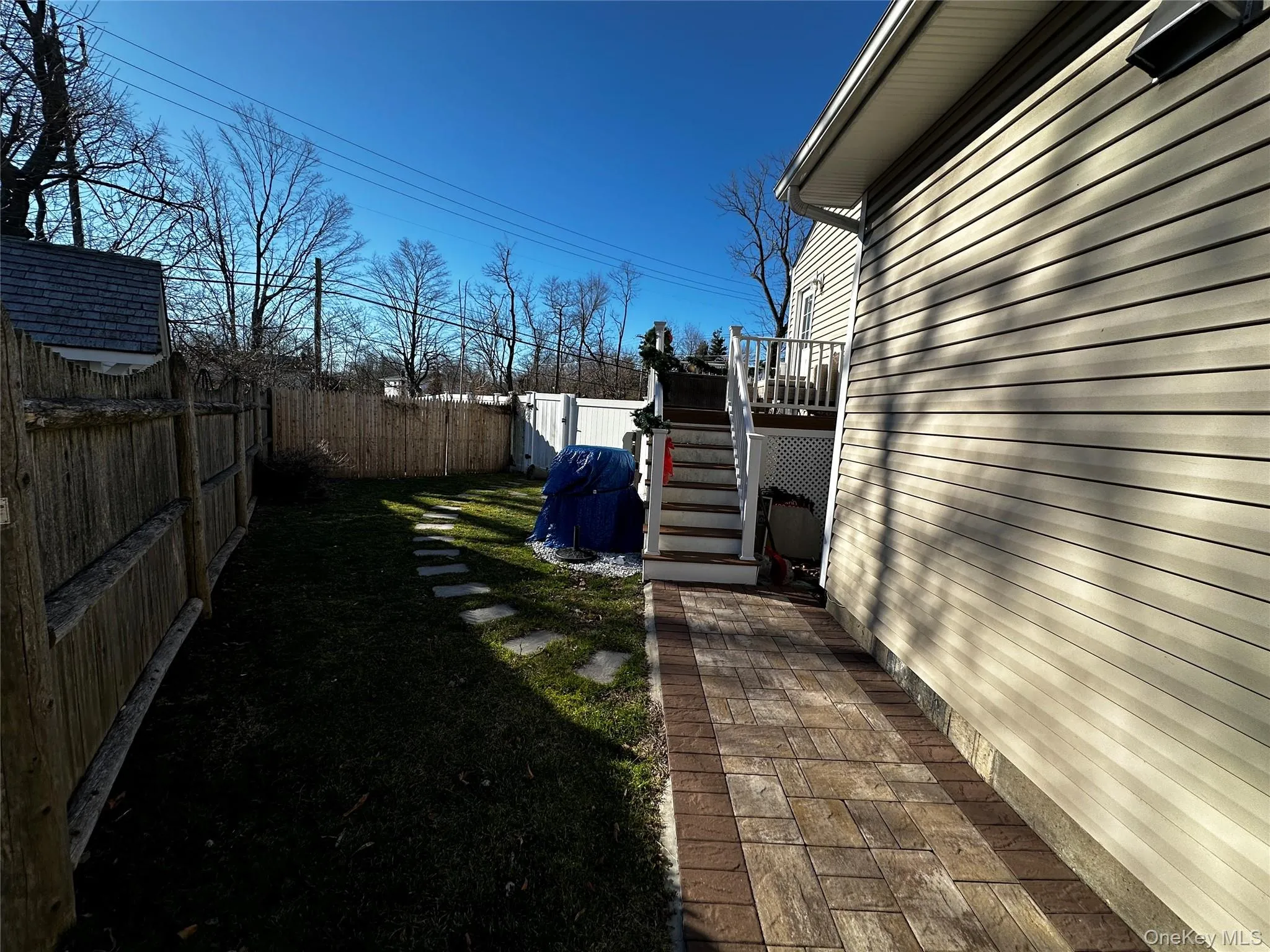 Side yard featuring a paver walkway, vinyl siding, and a wooden privacy fence Side yard featuring a paver walkway, vinyl siding, and a wooden privacy fence