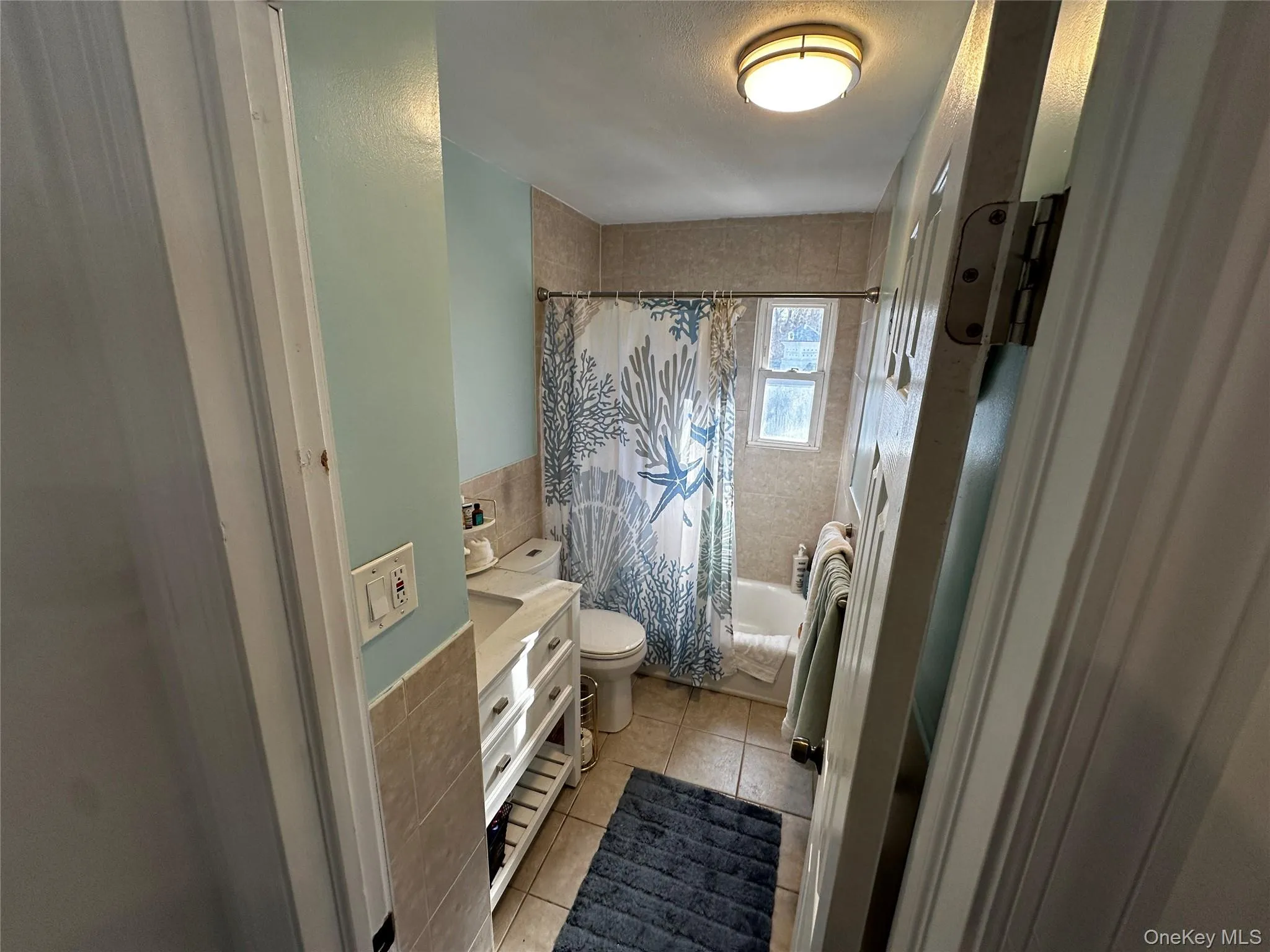 Bathroom featuring a white vanity with drawers and open shelving, a white toilet, and a bathtub with an overhead shower Bathroom featuring a white vanity with drawers and open shelving, a white toilet, and a bathtub with an overhead shower