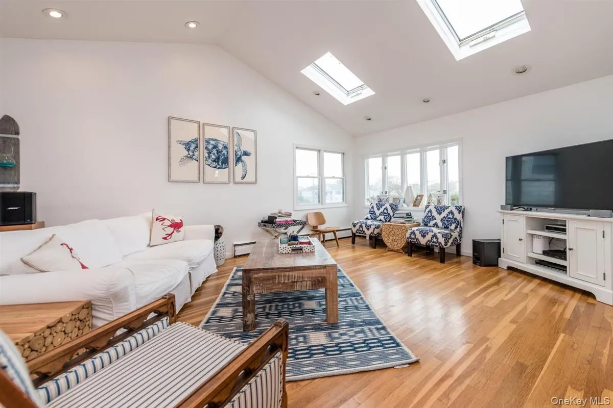 Vaulted ceiling great room featuring recessed lighting, skylights, wood-finish flooring, and multiple windows Vaulted ceiling great room featuring recessed lighting, skylights, wood-finish flooring, and multiple windows
