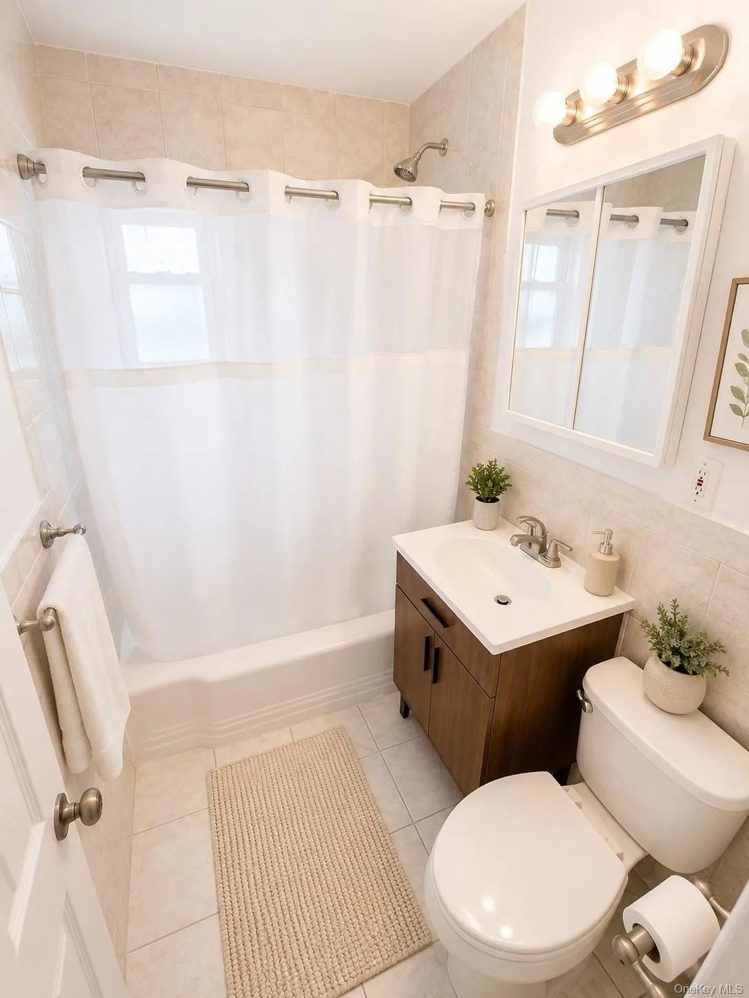 Full bathroom featuring a shower-over-tub combination with tile surround, a built-in vanity with under-sink storage, a mirrored medicine cabinet, and tiled flooring Full bathroom featuring a shower-over-tub combination with tile surround, a built-in vanity with under-sink storage, a mirrored medicine cabinet, and tiled flooring