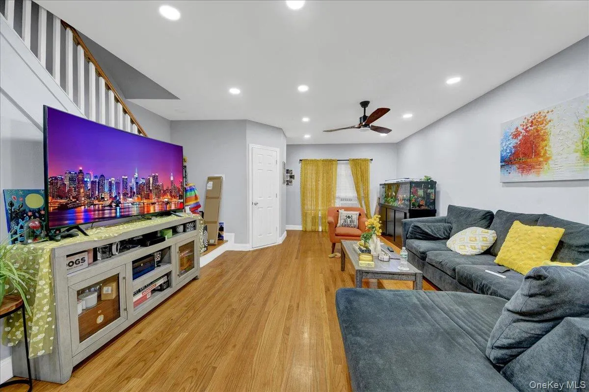 Spacious living area featuring wood-finish flooring, recessed lighting, a ceiling fan, and a light-colored wall palette Spacious living area featuring wood-finish flooring, recessed lighting, a ceiling fan, and a light-colored wall palette