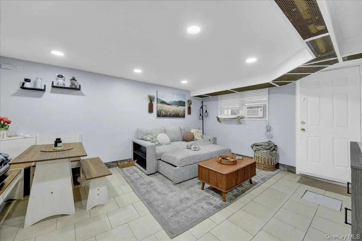 Open-concept living area featuring light-toned tile flooring, recessed ceiling lighting, and light blue wall tones Open-concept living area featuring light-toned tile flooring, recessed ceiling lighting, and light blue wall tones