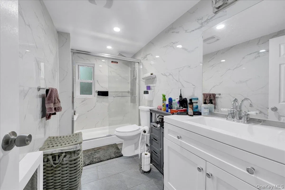 Contemporary bathroom featuring a white vanity with integrated sink, chrome fixtures, and a large wall-mounted mirror Contemporary bathroom featuring a white vanity with integrated sink, chrome fixtures, and a large wall-mounted mirror