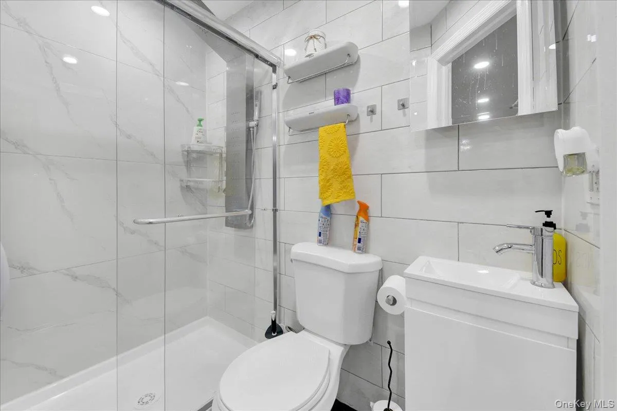 Modern bathroom featuring a glass-enclosed shower with a white tiled surround and a white shower pan Modern bathroom featuring a glass-enclosed shower with a white tiled surround and a white shower pan