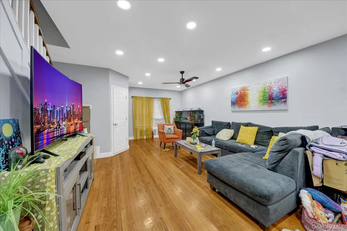 Spacious living area featuring wood-finish flooring, recessed lighting, and light gray wall tones Spacious living area featuring wood-finish flooring, recessed lighting, and light gray wall tones