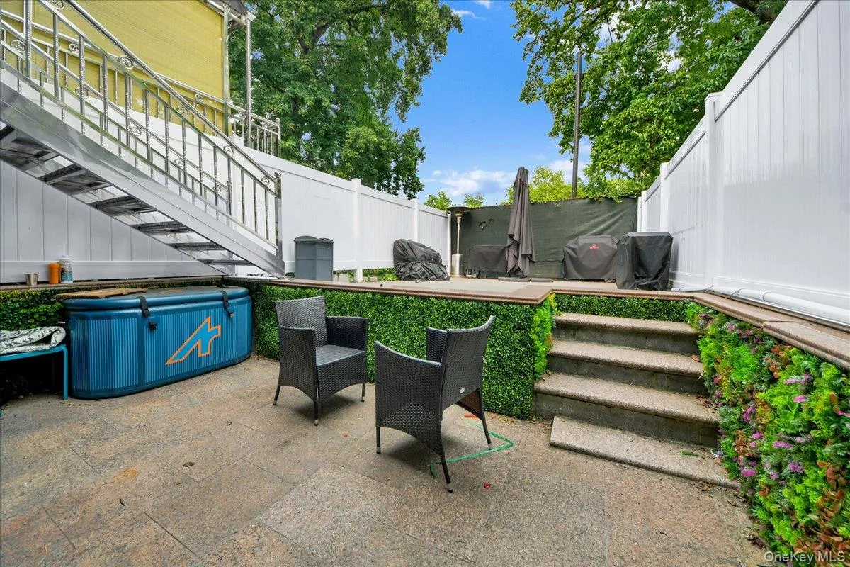 Patio area featuring stone-finish pavers, a tiered layout with steps, and privacy fencing Patio area featuring stone-finish pavers, a tiered layout with steps, and privacy fencing