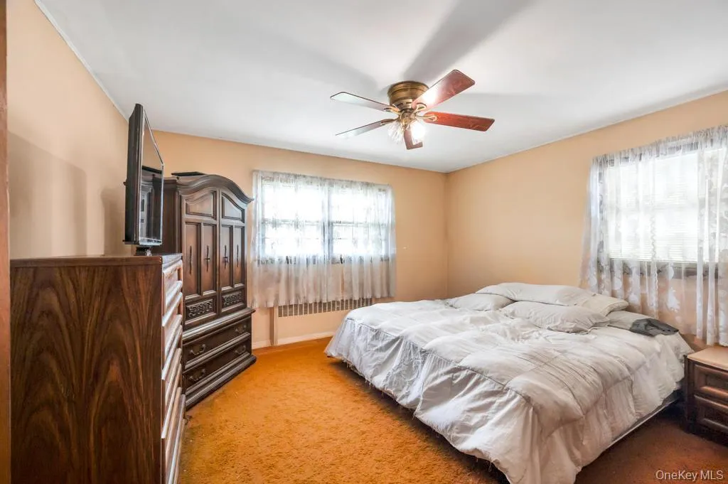 Bedroom with wall-to-wall carpeting, two windows, and a ceiling fan with light fixture Bedroom with wall-to-wall carpeting, two windows, and a ceiling fan with light fixture