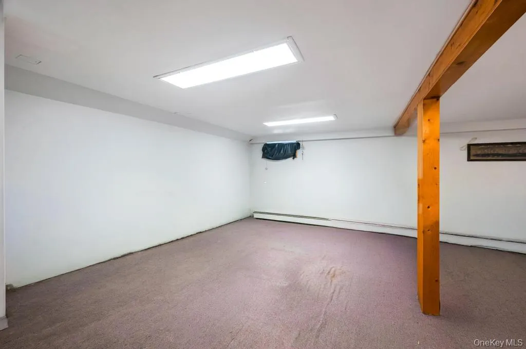 Spacious room featuring carpet flooring, white walls, and bright overhead lighting Spacious room featuring carpet flooring, white walls, and bright overhead lighting