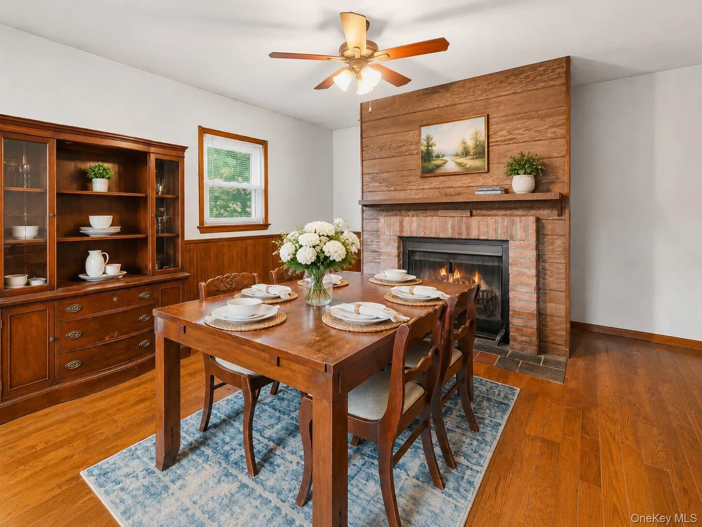 Virtually Staged Dining Area: Warm and inviting formal dining room featuring hardwood floors, a brick fireplace, wood accent details, and plenty of room for gatherings. Virtually Staged Dining Area: Warm and inviting formal dining room featuring hardwood floors, a brick fireplace, wood accent details, and plenty of room for gatherings.