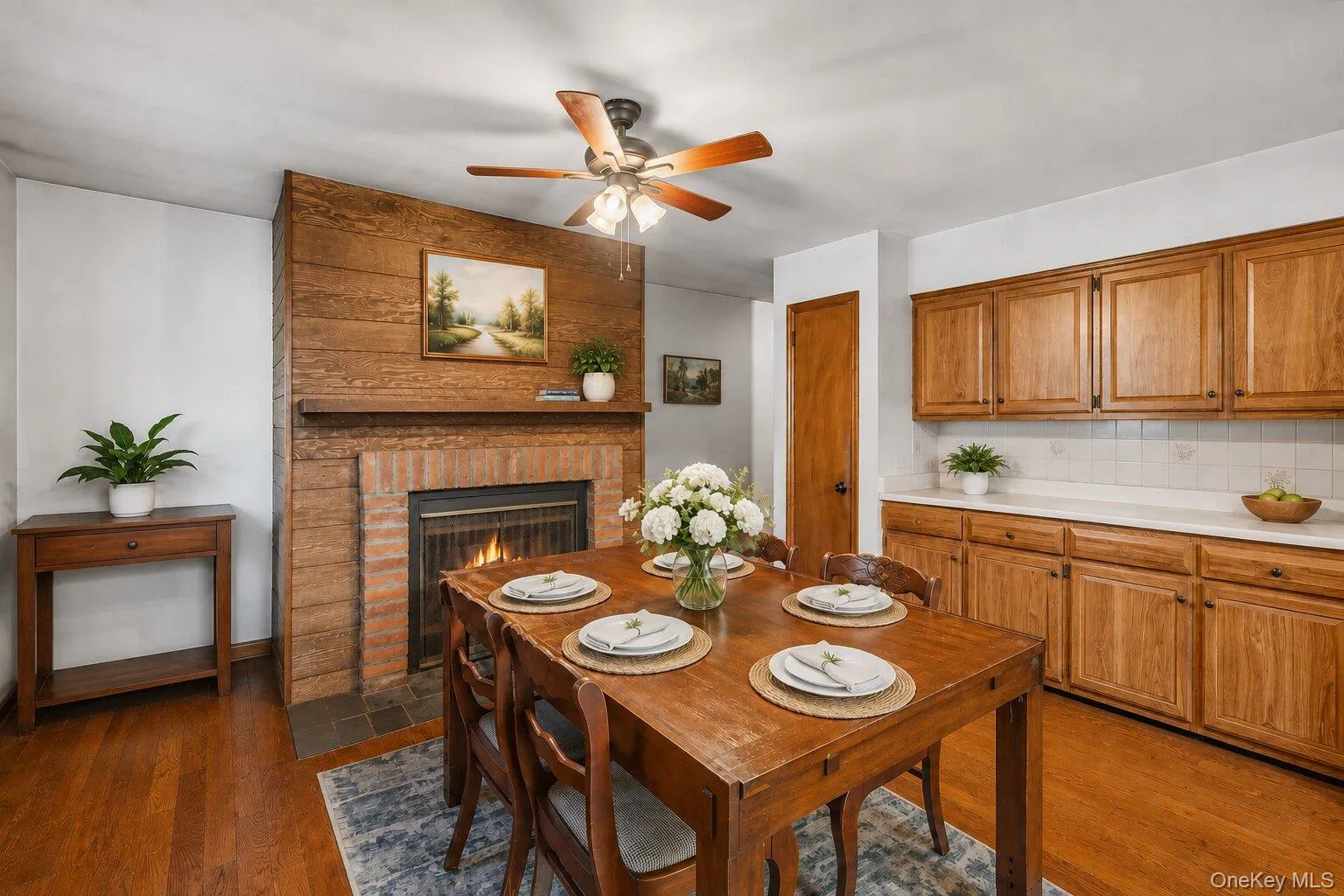 Virtually Staged Dining Area: Warm and inviting formal dining room featuring hardwood floors, a brick fireplace, wood accent details, and plenty of room for gatherings. Virtually Staged Dining Area: Warm and inviting formal dining room featuring hardwood floors, a brick fireplace, wood accent details, and plenty of room for gatherings.