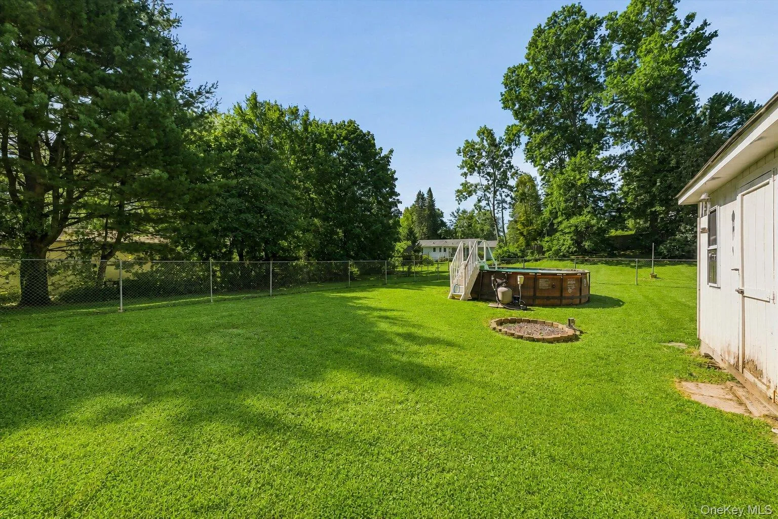 Spacious fenced backyard with an above-ground pool, storage shed, deck, and enclosed rear addition overlooking the property. Spacious fenced backyard with an above-ground pool, storage shed, deck, and enclosed rear addition overlooking the property.