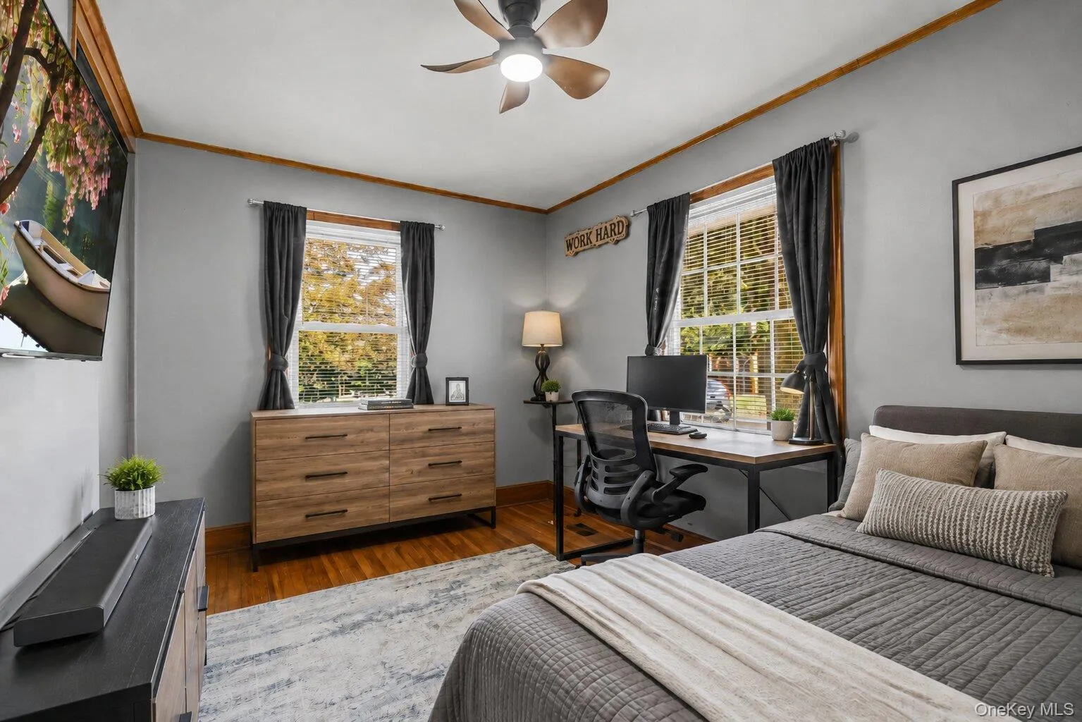 Virtually Staged Bedroom and Workspace: Additional view of the versatile bedroom featuring a bed, dresser, workstation, hardwood floors, and multiple windows. Virtually Staged Bedroom and Workspace: Additional view of the versatile bedroom featuring a bed, dresser, workstation, hardwood floors, and multiple windows.