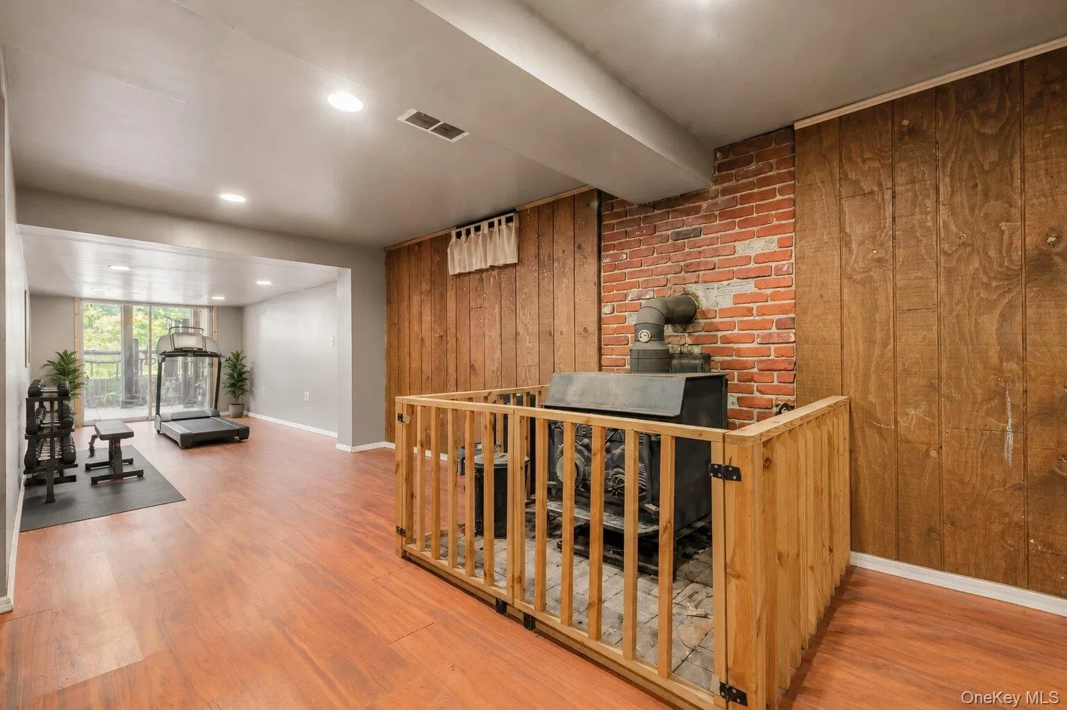 Virtually Staged. Finished lower-level space featuring wood-look flooring, recessed lighting, a brick chimney with a supplemental stove, and room for exercise equipment or hobbies. Virtually Staged. Finished lower-level space featuring wood-look flooring, recessed lighting, a brick chimney with a supplemental stove, and room for exercise equipment or hobbies.