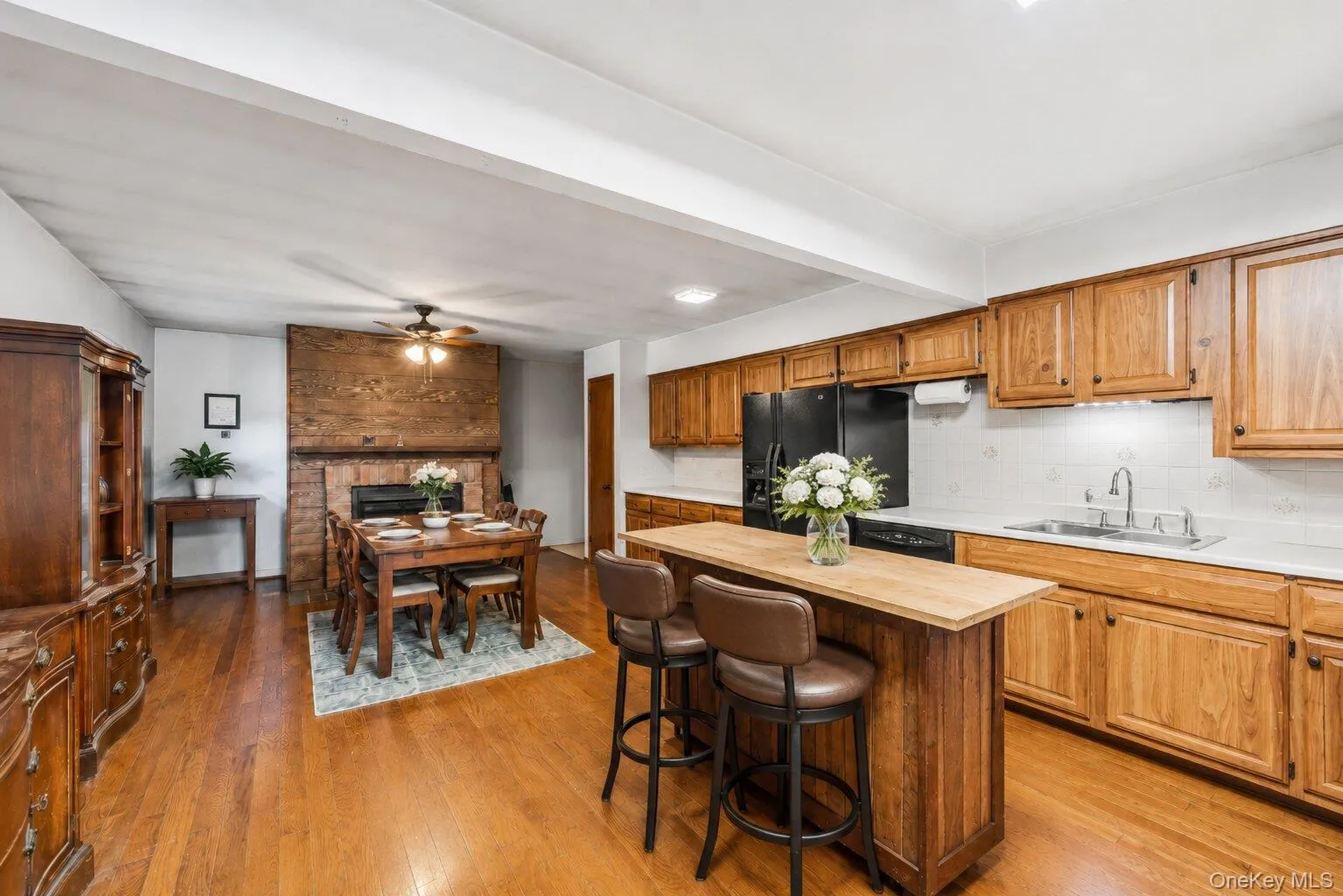 Spacious kitchen featuring abundant wood cabinetry, black appliances, hardwood floors, a center island, and seating for two. Spacious kitchen featuring abundant wood cabinetry, black appliances, hardwood floors, a center island, and seating for two.