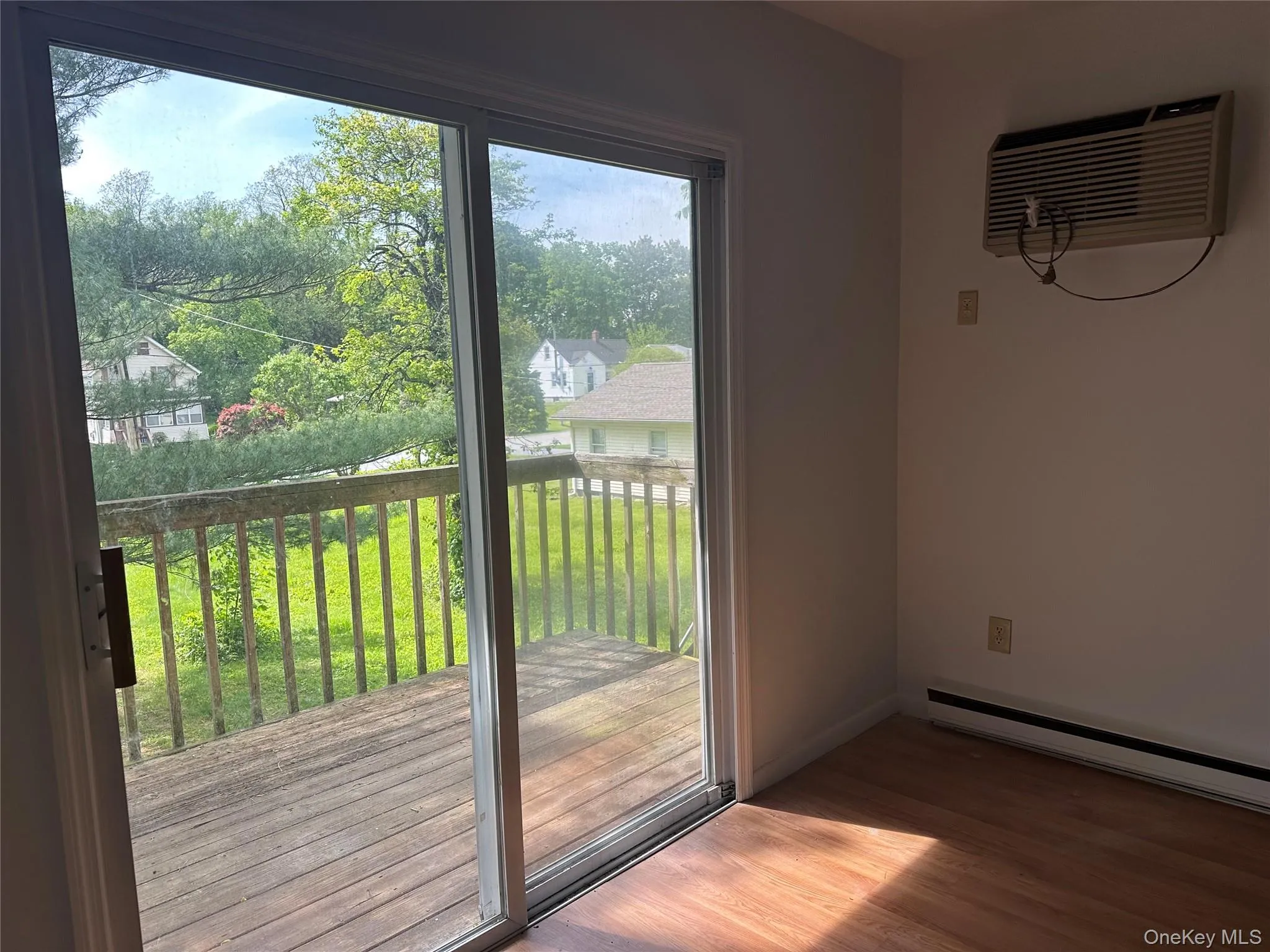 Doorway with a wall mounted air conditioner, wood finished floors, a baseboard heating unit, and baseboards Doorway with a wall mounted air conditioner, wood finished floors, a baseboard heating unit, and baseboards
